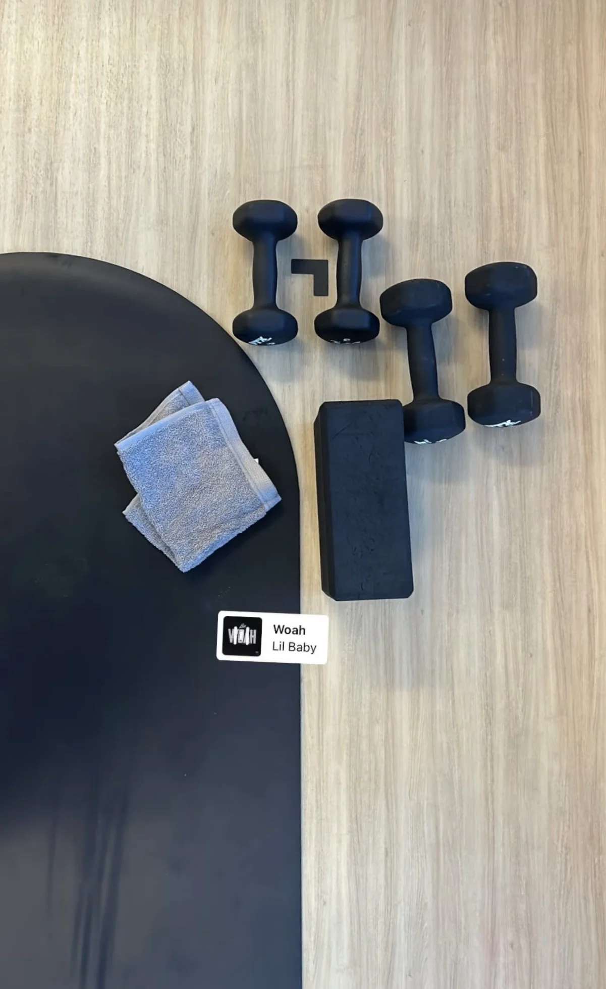 the negro mate wellness mat rolled out on hardwood floor with a block, weights, and towel.