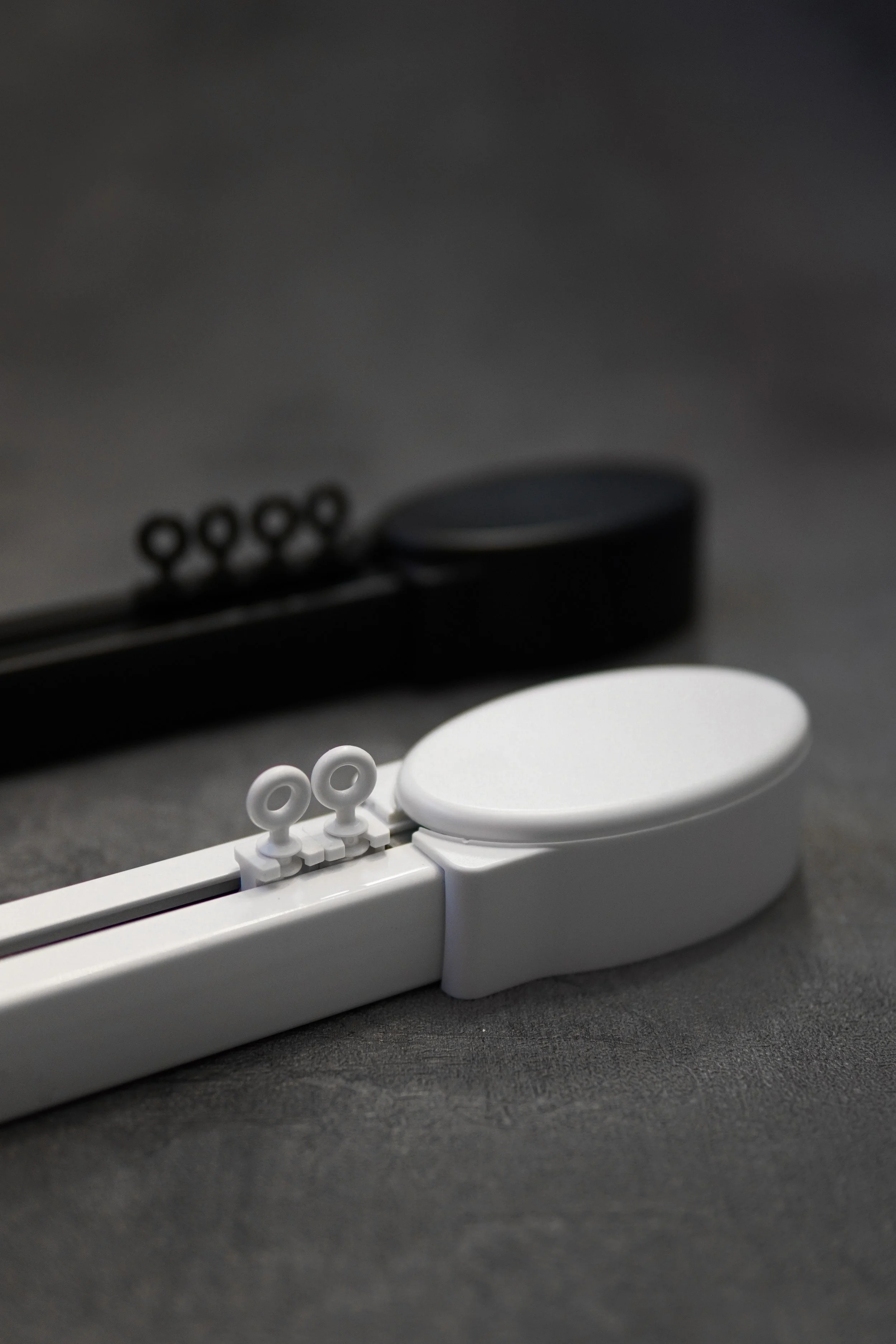 Close-up of two electric, motorised, Somfy tracks, one black and one white