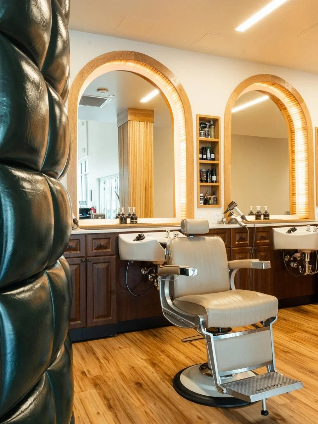Custom walnut millwork and professional styling stations inside the flagship RiNo barbershop.