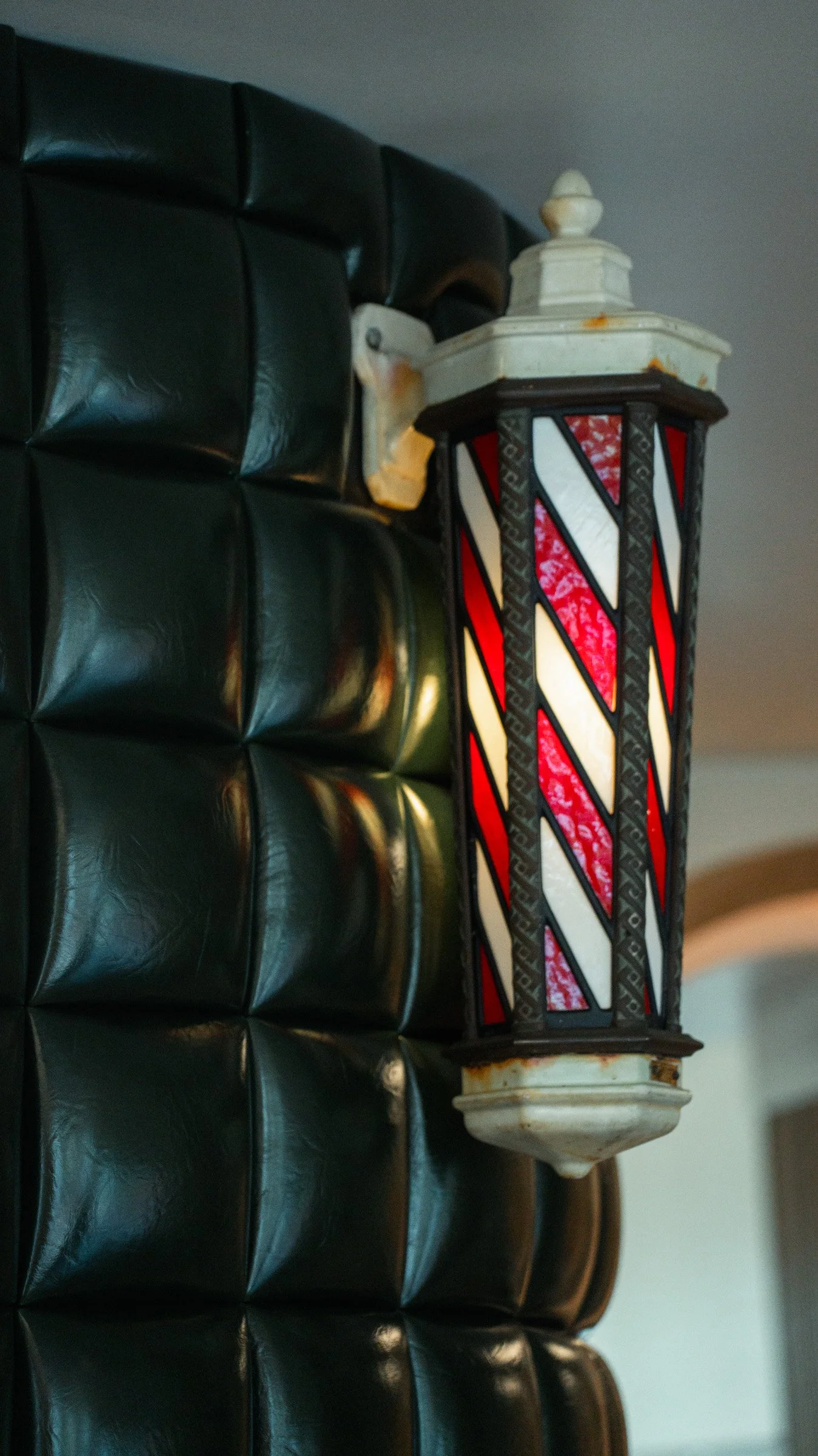 Vintage Koken stained glass barber pole from 1890 at The Rosemont Barbers Rino, on upholstered wall with hidden door. 