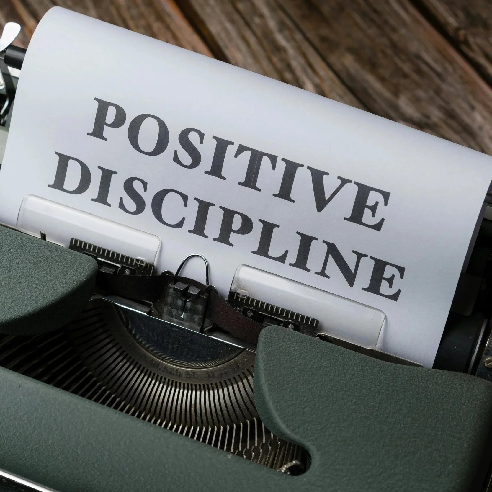 A vintage typewriter feeds out a sheet of paper reading "positive discipline," symbolizing intention, structure, and mindful productivity.