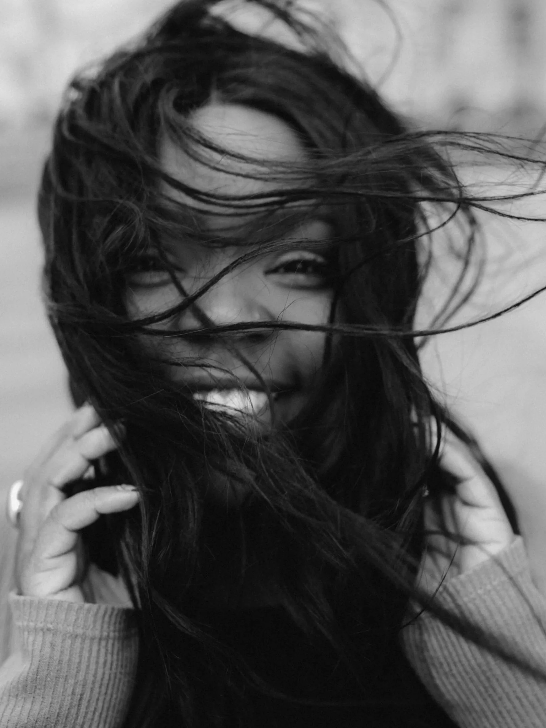 Confident woman smiling with wind blowing through her hair, symbolizing clarity, confidence, and personal growth in a success journey.