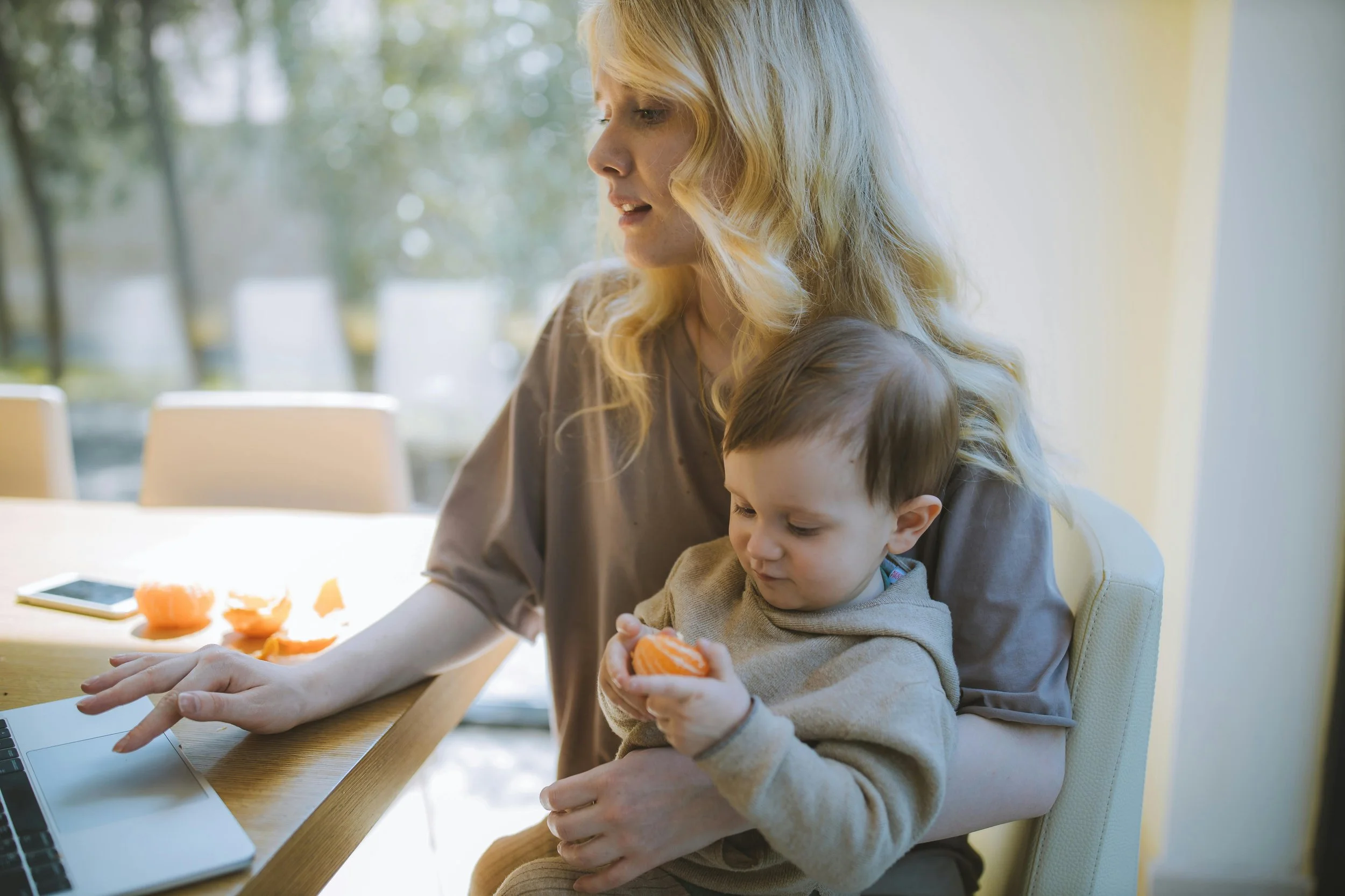 Mother working on a laptop while holding her baby, balancing productivity and real life responsibilities in a calm, intentional routine