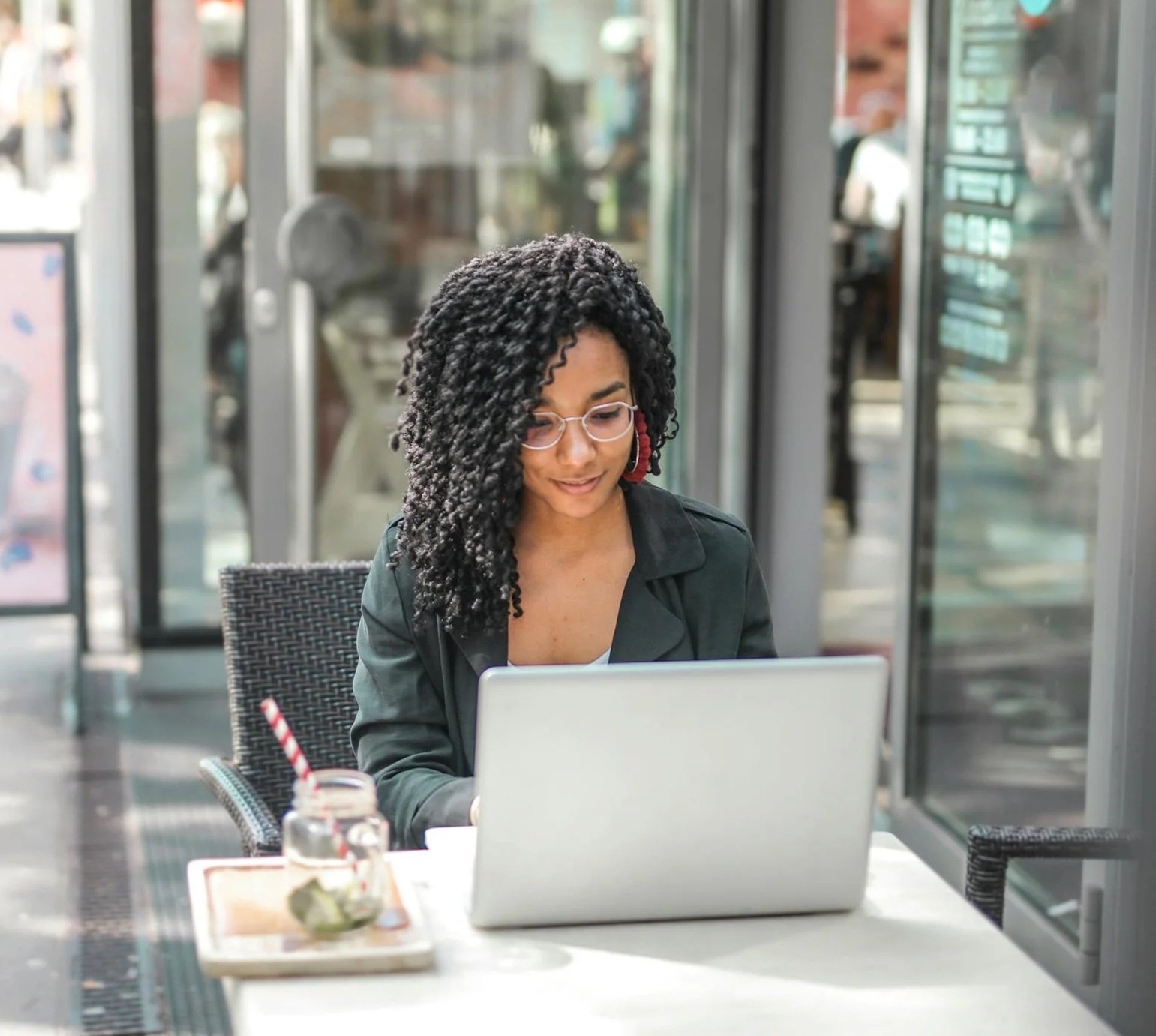 Woman working on a laptop at an outdoor café table, representing focused productivity, intentional work habits, and flow based living.