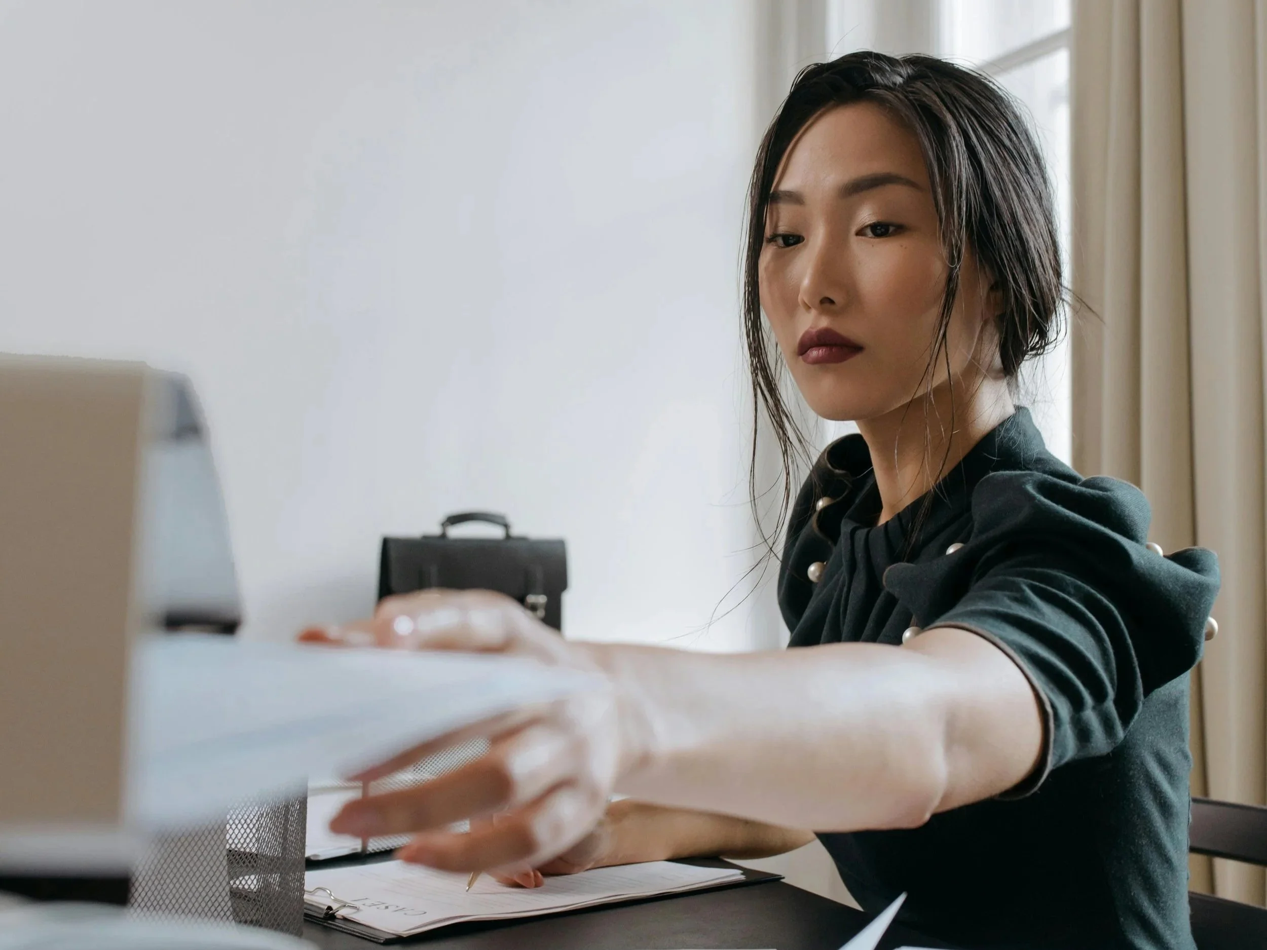 A focused woman working at a desk with papers and a laptop, symbolizing intentional work, clarity, and aligned decision making in a calm environment.