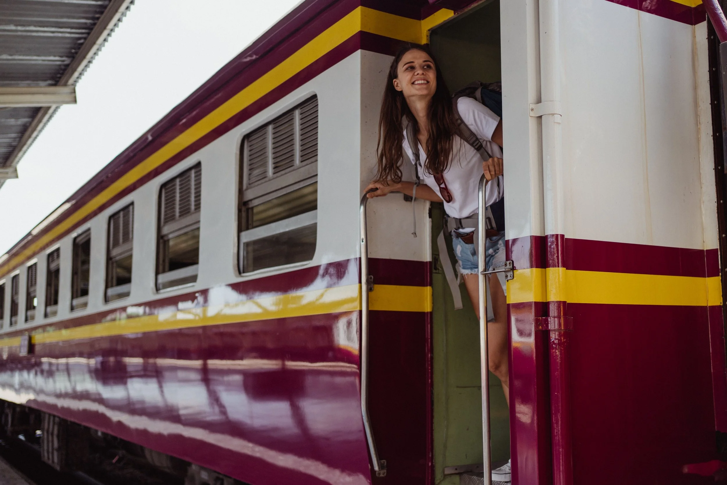 Woman leaning out of train door, excited for where her life journey will  take her