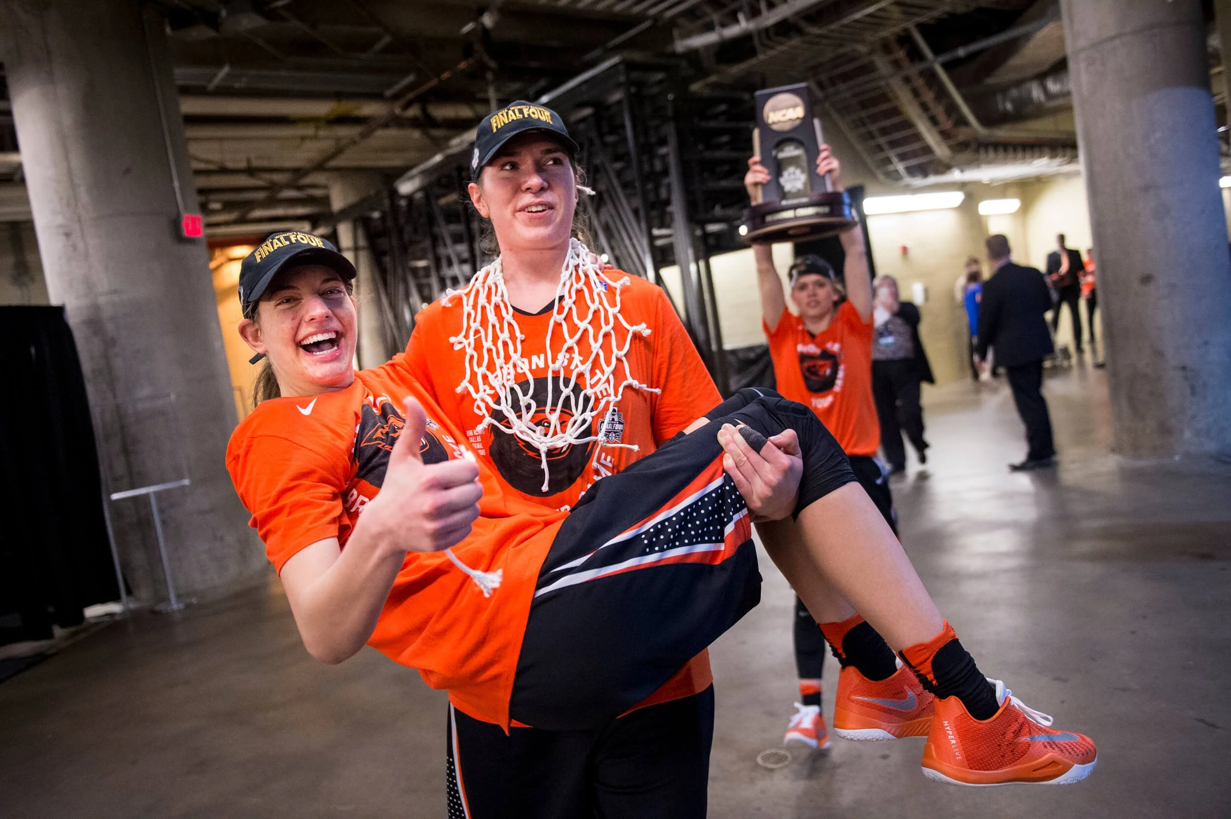 Ruth Hamblin carrying Sydney Wiese across the alter after OSU’s Elite Eight win over Baylor in 2016. Jamie Weisner stands in background with trophy (courtesy Karl Maasdam)