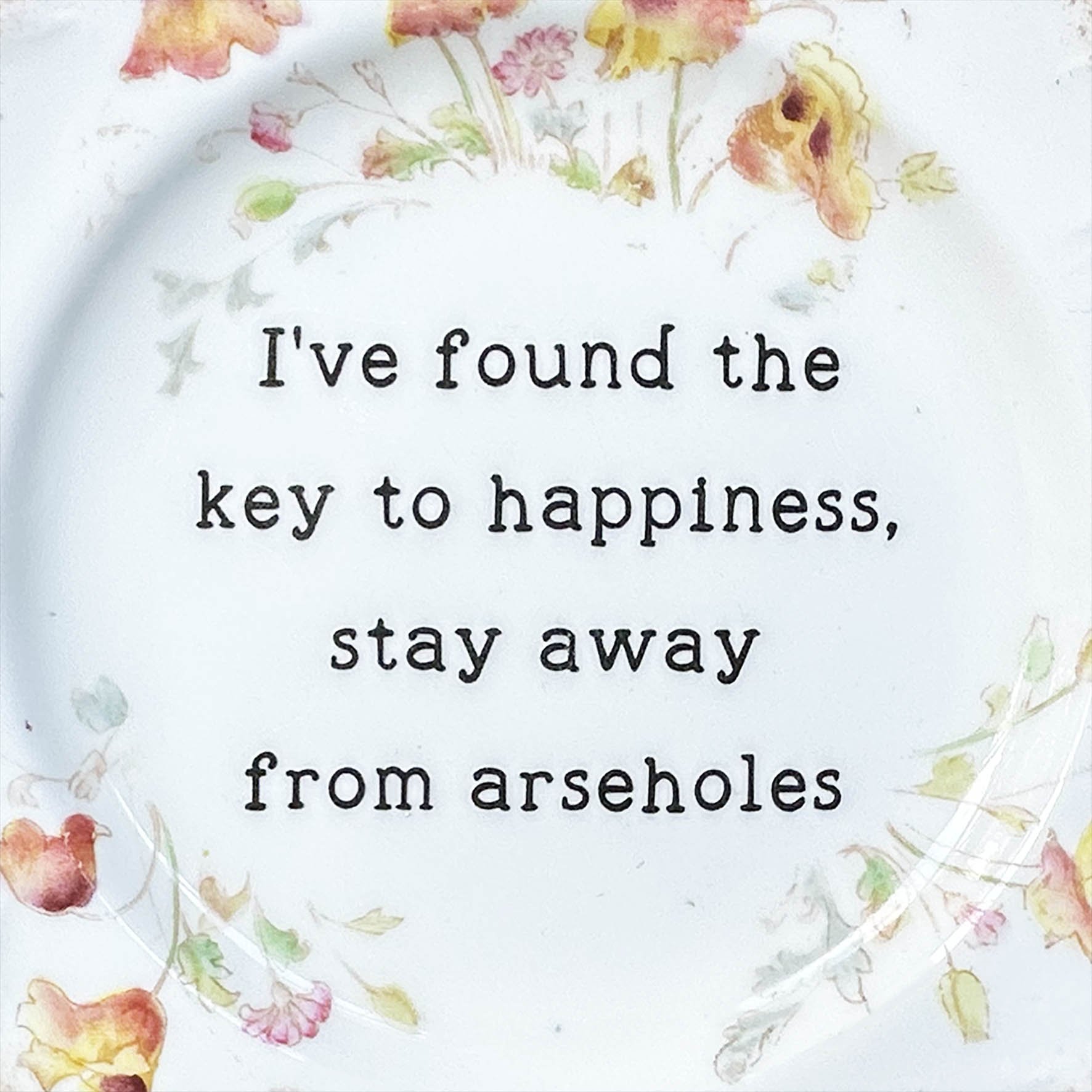 A vintage decorative plate with a quote “I’ve found the key to happiness, stay away from arseholes”
