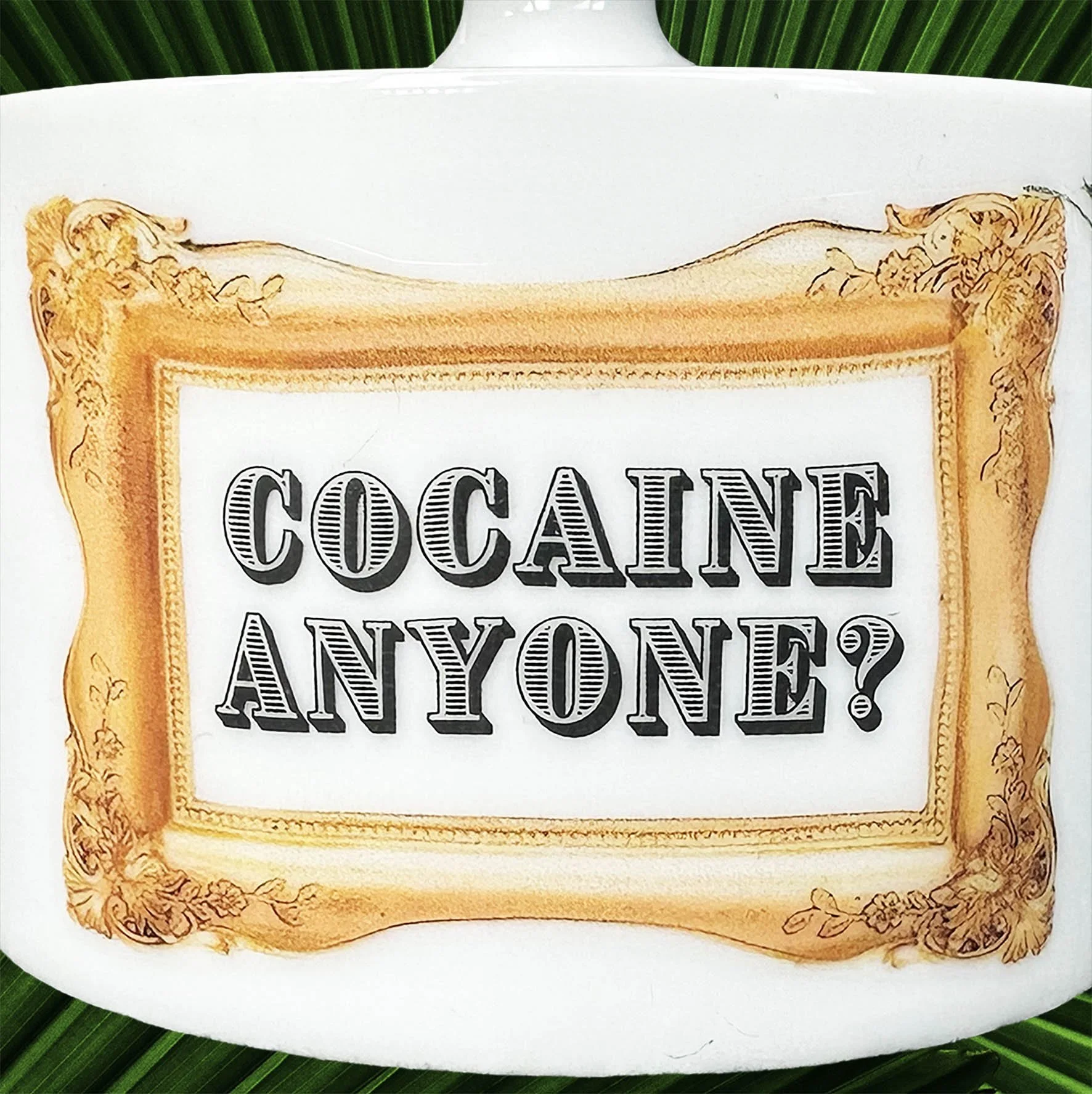A vintage Thomas Germany sugar bowl with the words “cocaine anyone?” Inside a gold frame