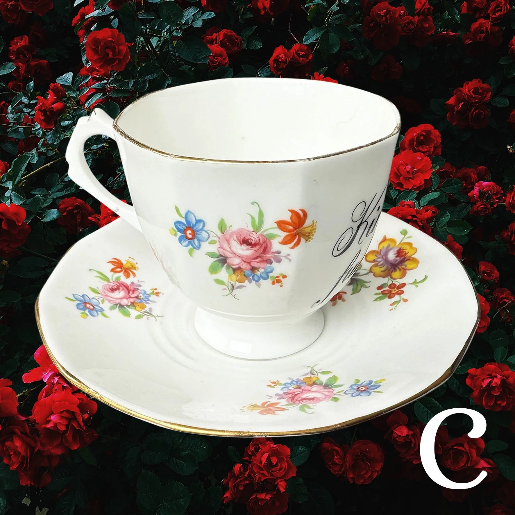 Vintage tea cup and saucer with a floral design and the words "kindly fuck off" in black writing