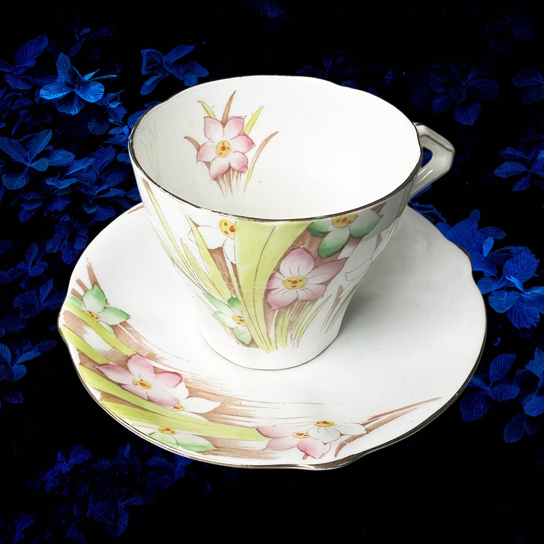 A vintage tea cup with a floral design and the words "we're all mad here" in black writing