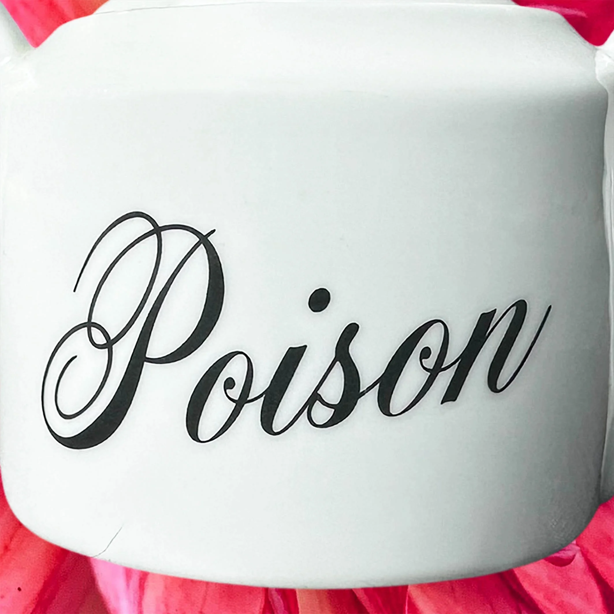 A white sugar bowl with handles and a lid and the words “poison” in black cursive writing