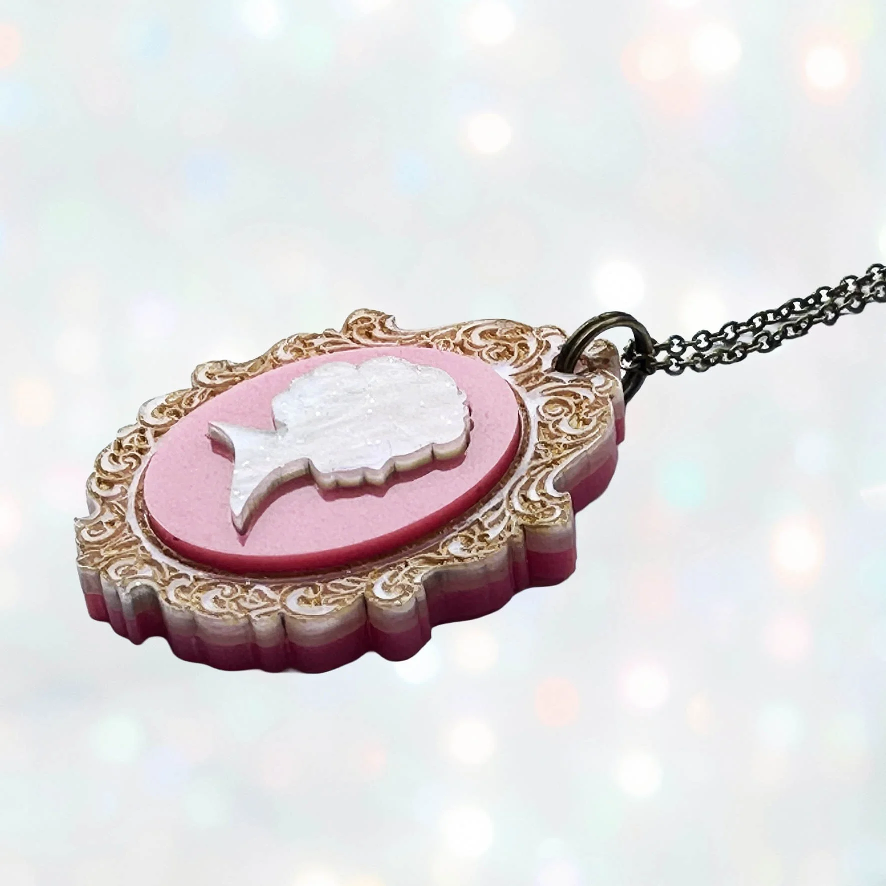 A laser cut pink and gold acrylic cameo style necklace featuring a silhouette