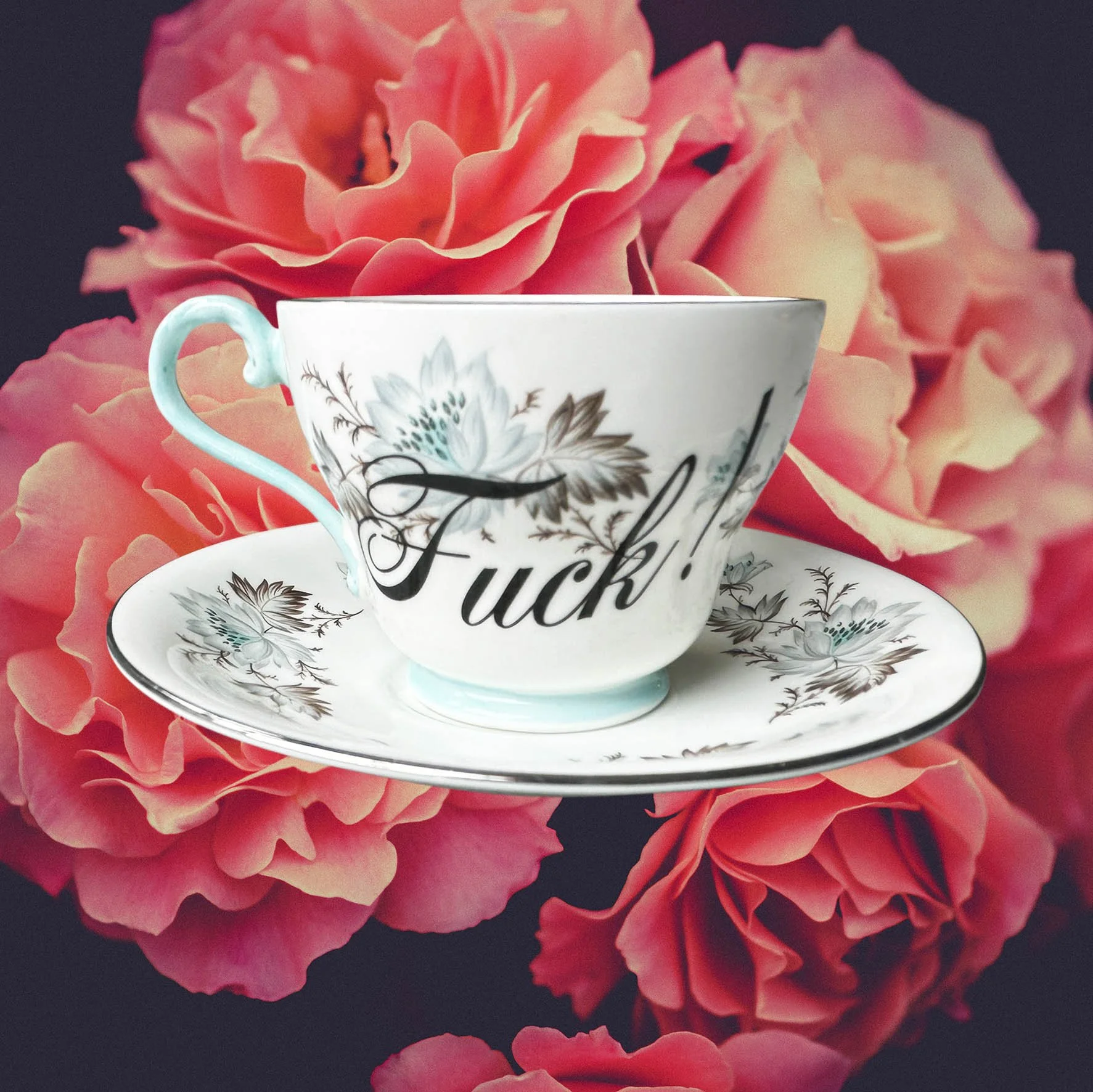 a vintage tea cup and saucer with a blue floral design and the word "fuck!" in black writing