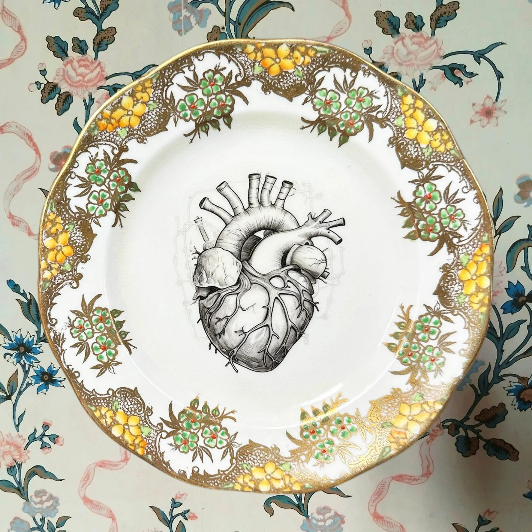 A cream and gold vintage plate with a picture of an anatomical heart