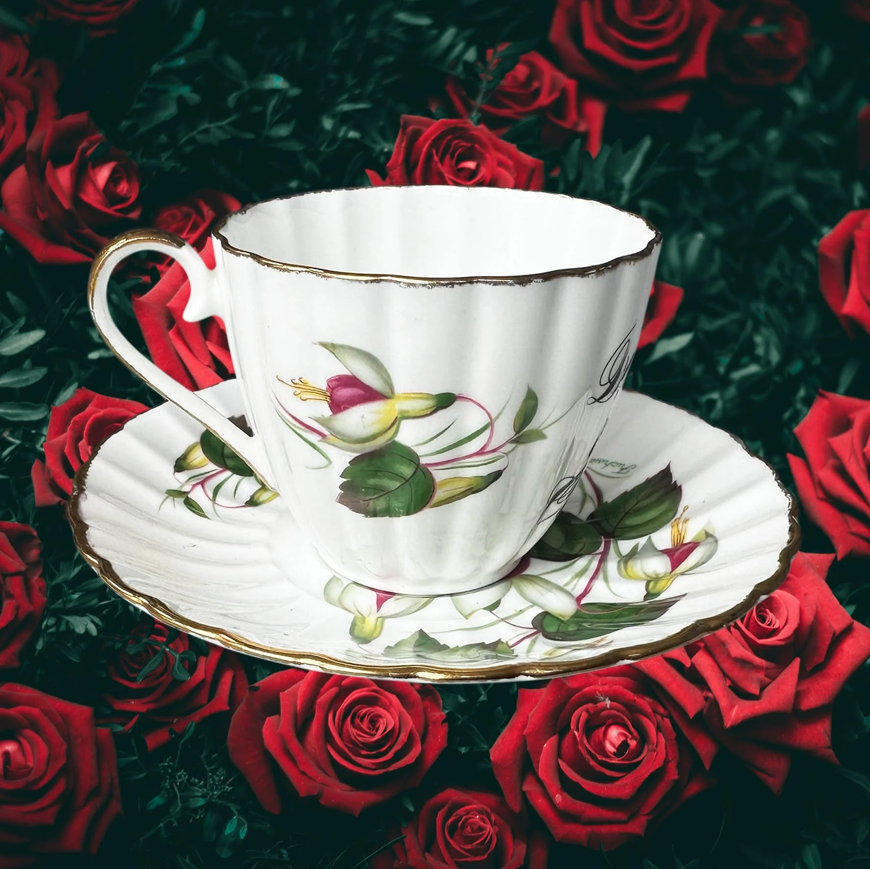A vintage tea cup with a fuchsia design and the words "don't be a cunt" in black writing
