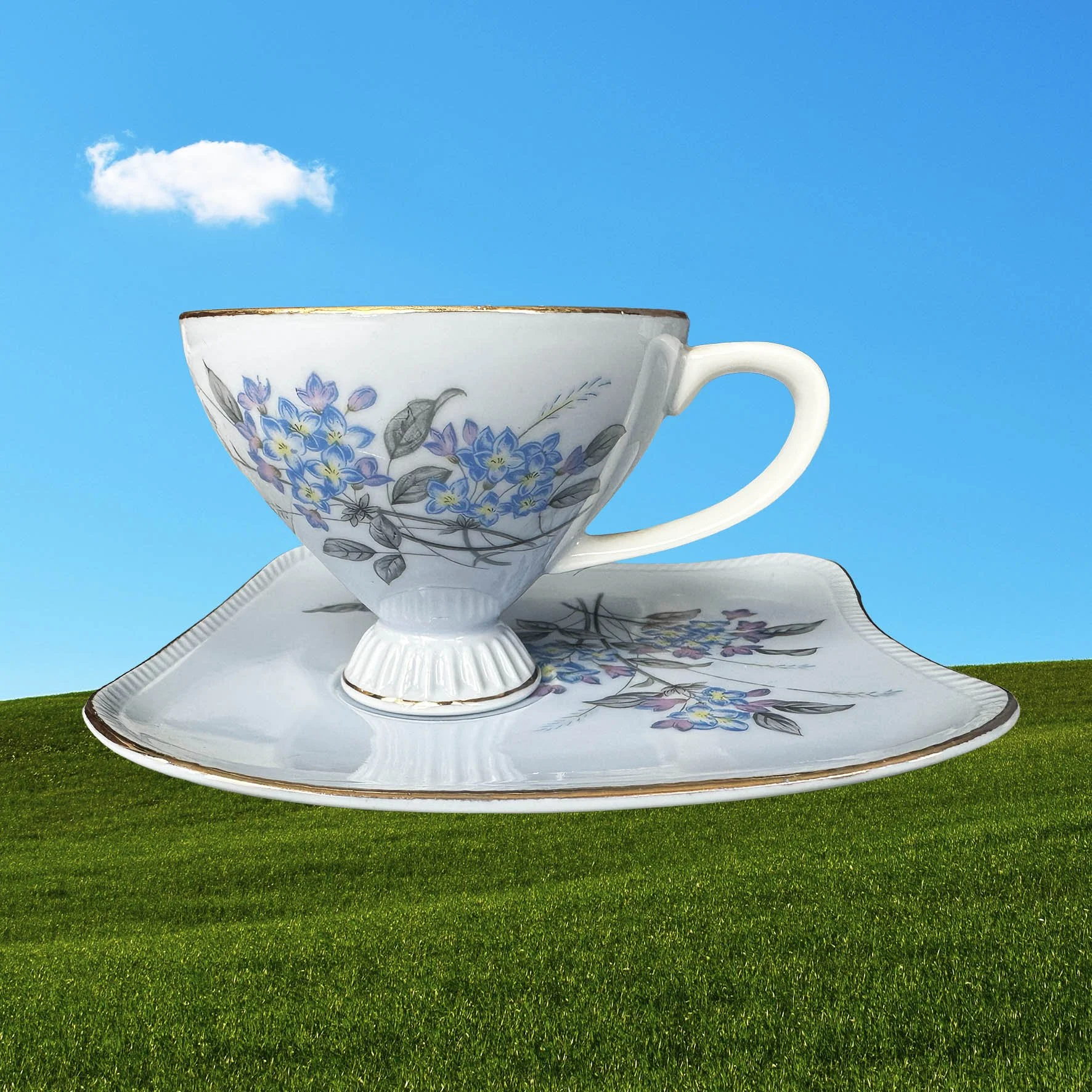 A blue tea cup and saucer set with a blue floral design and the words “rise and fucking shine” in black cursive writing
