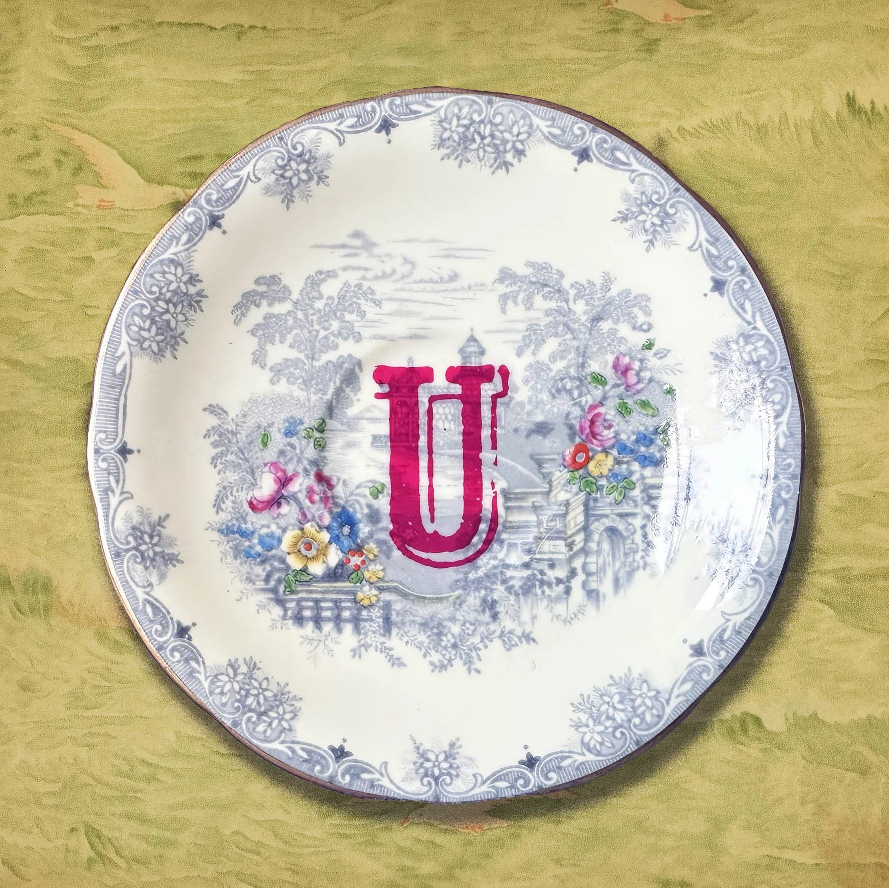 A vintage saucer with an orange pink letter U