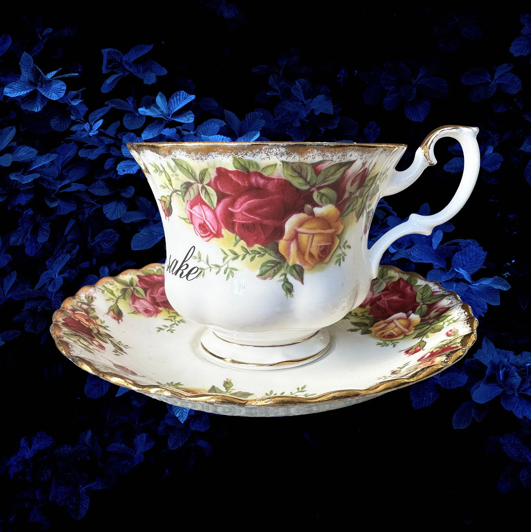 a vintage tea cup with a red rose design and the words "for fuck's sake" in black writing