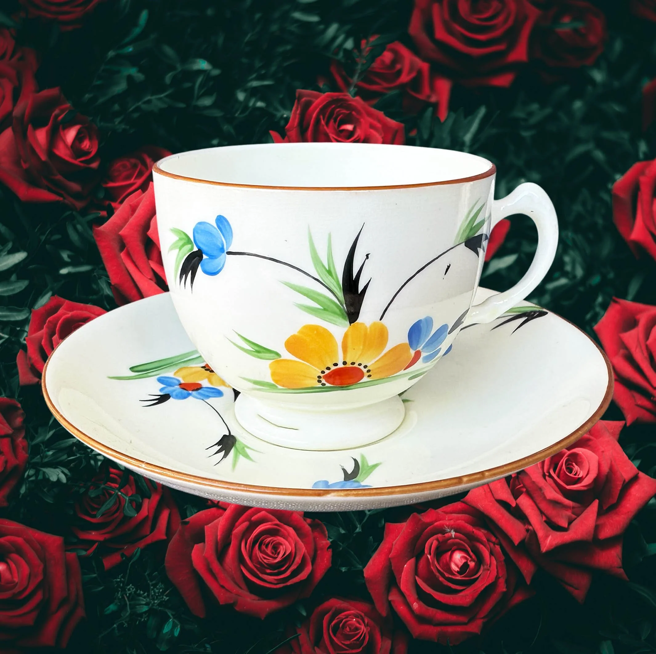 A vintage tea cup and saucer with a blue and green floral design, the words “breakfast wine” in black cursive writing