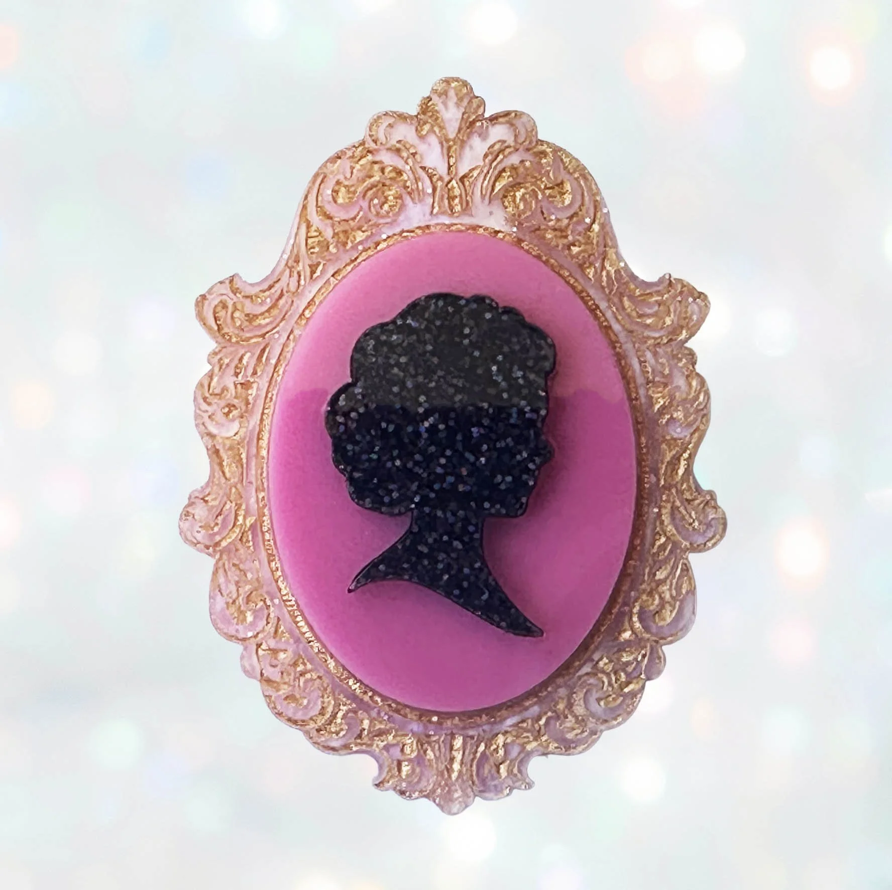A pink, black and gold glitter laser cut acrylic cameo style brooch featuring a silhouette