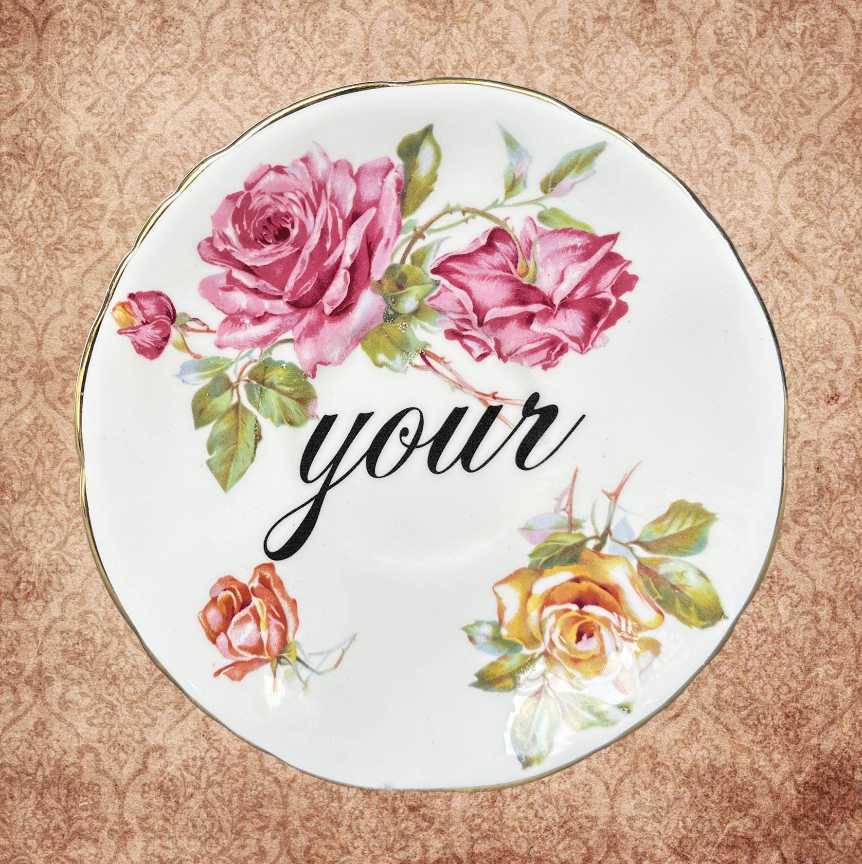 A saucer with a pink floral design and the word "your"