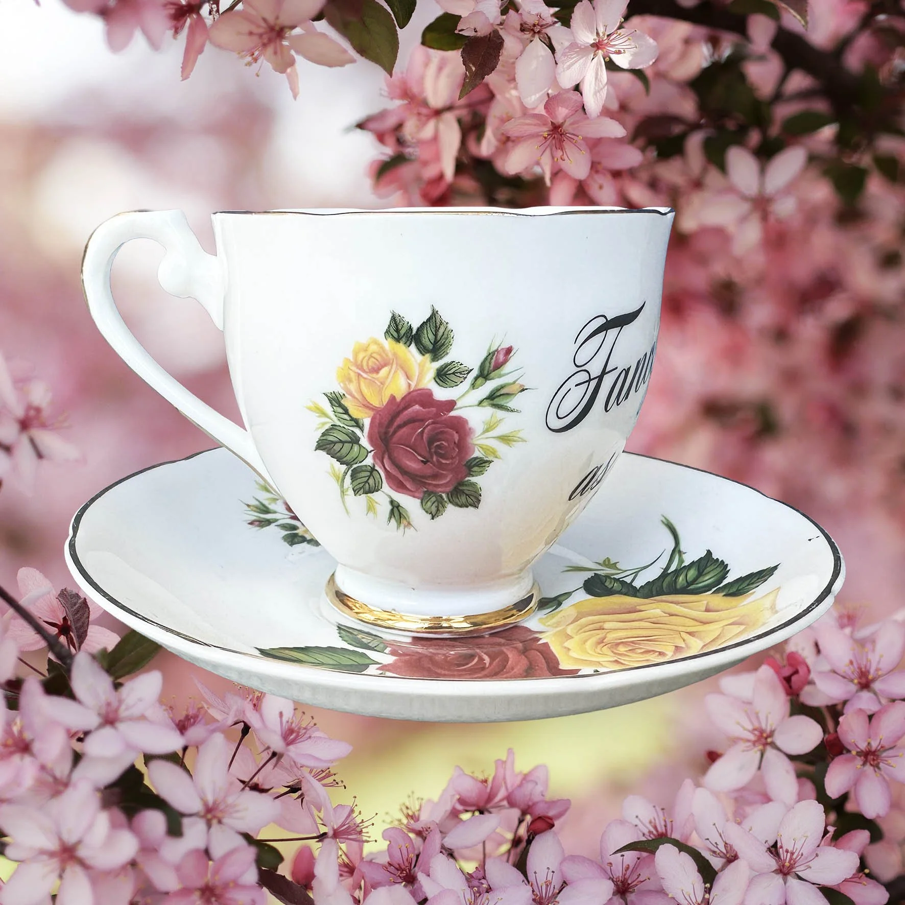 A vintage tea cup and saucer with a red and yellowfloral design, with the words "fancy as fuck" in black cursive writing