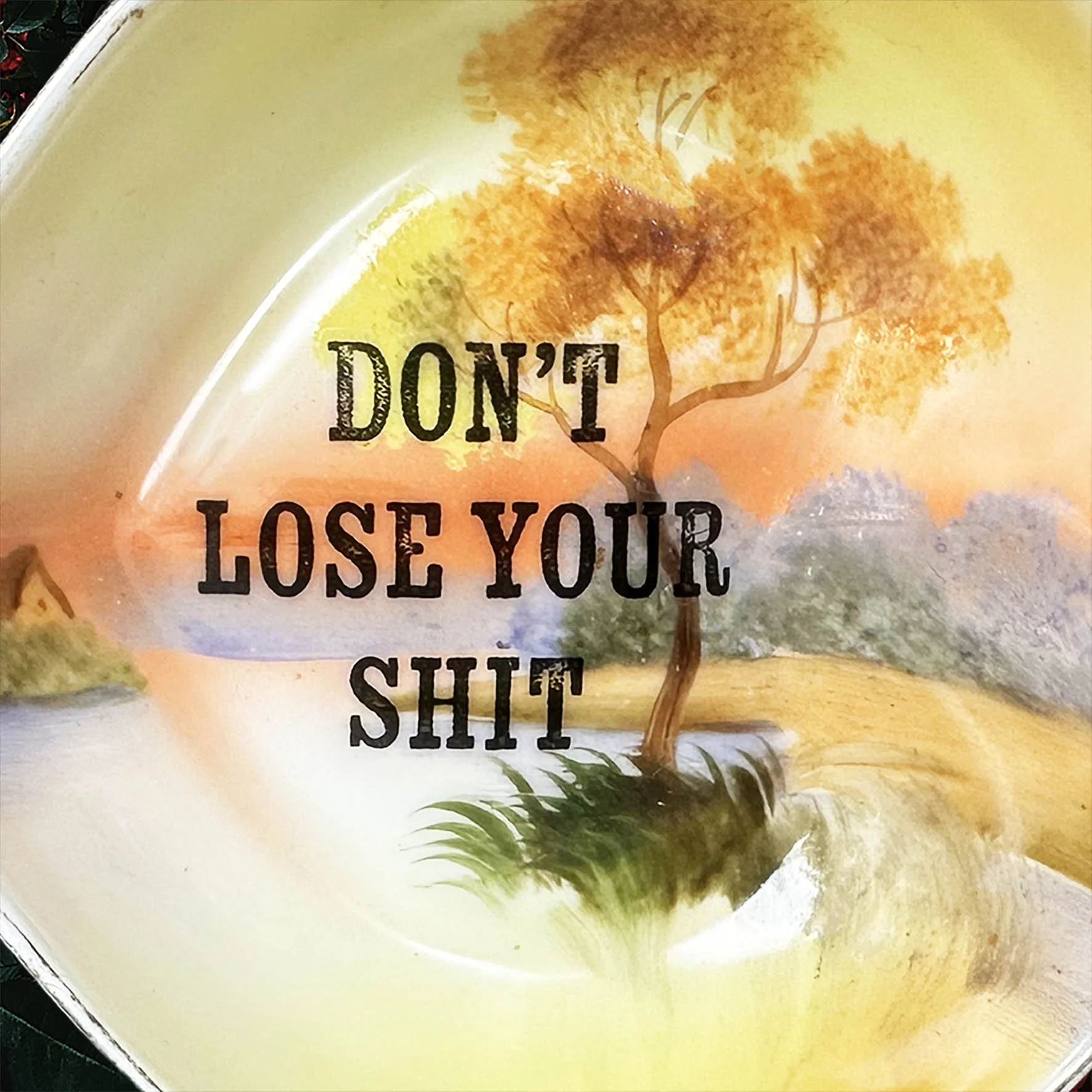 A heart shaped trinket dish with an orange, green and brown landscape design and the words “don’t lose your shit”