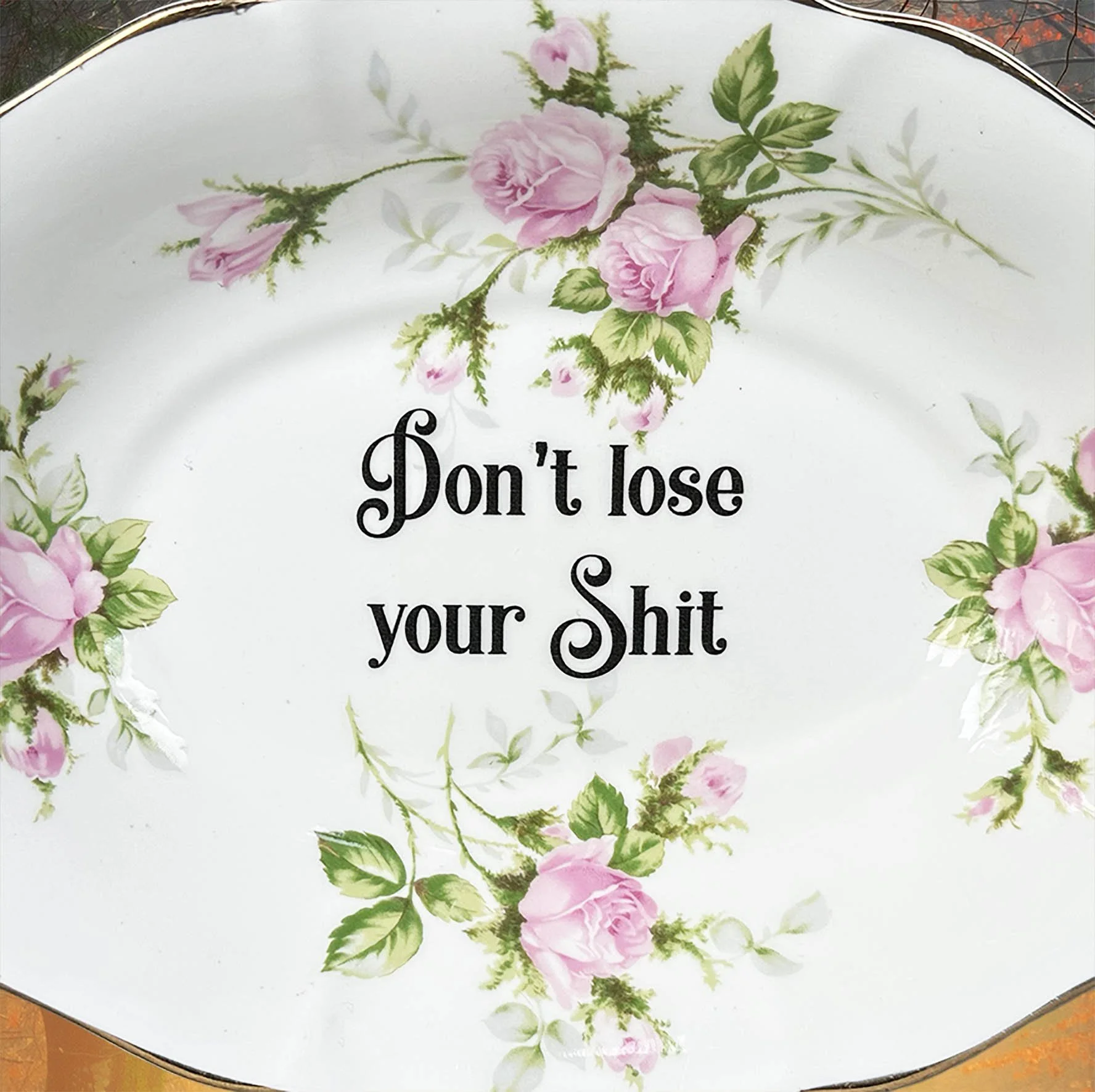 A vintage trinket dish with a pink floral design and the words “don’t lose your shit”