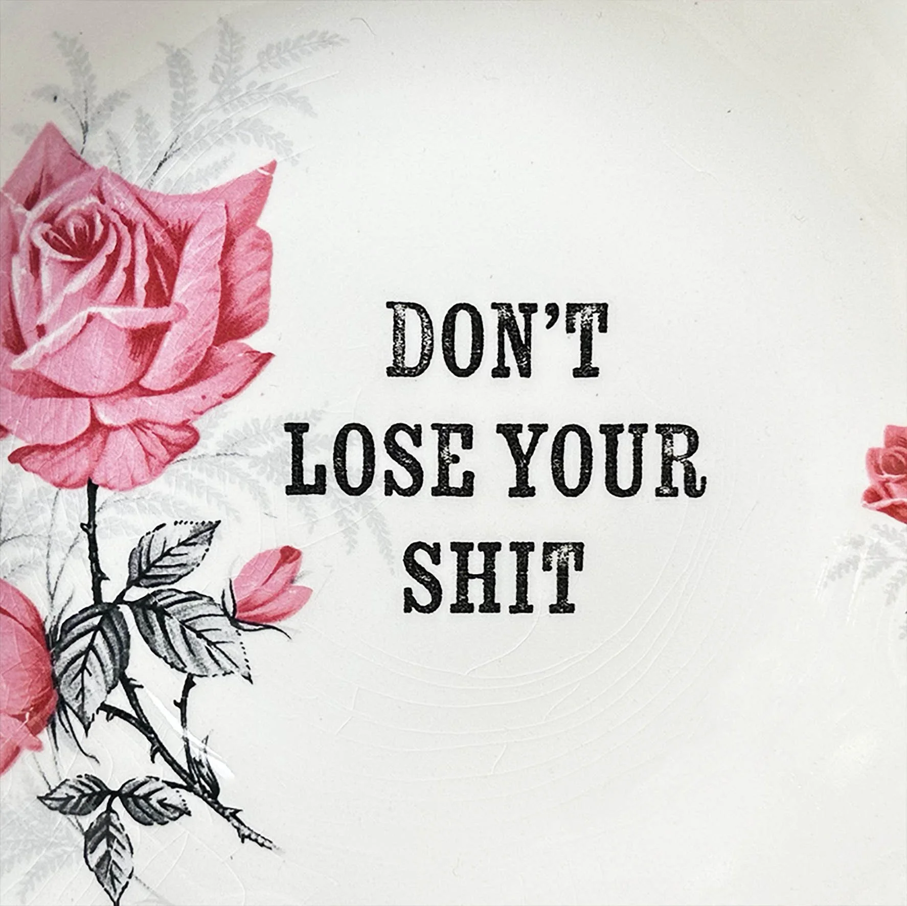 A vintage trinket dish with a pink floral design and the words “don’t lose your shit”
