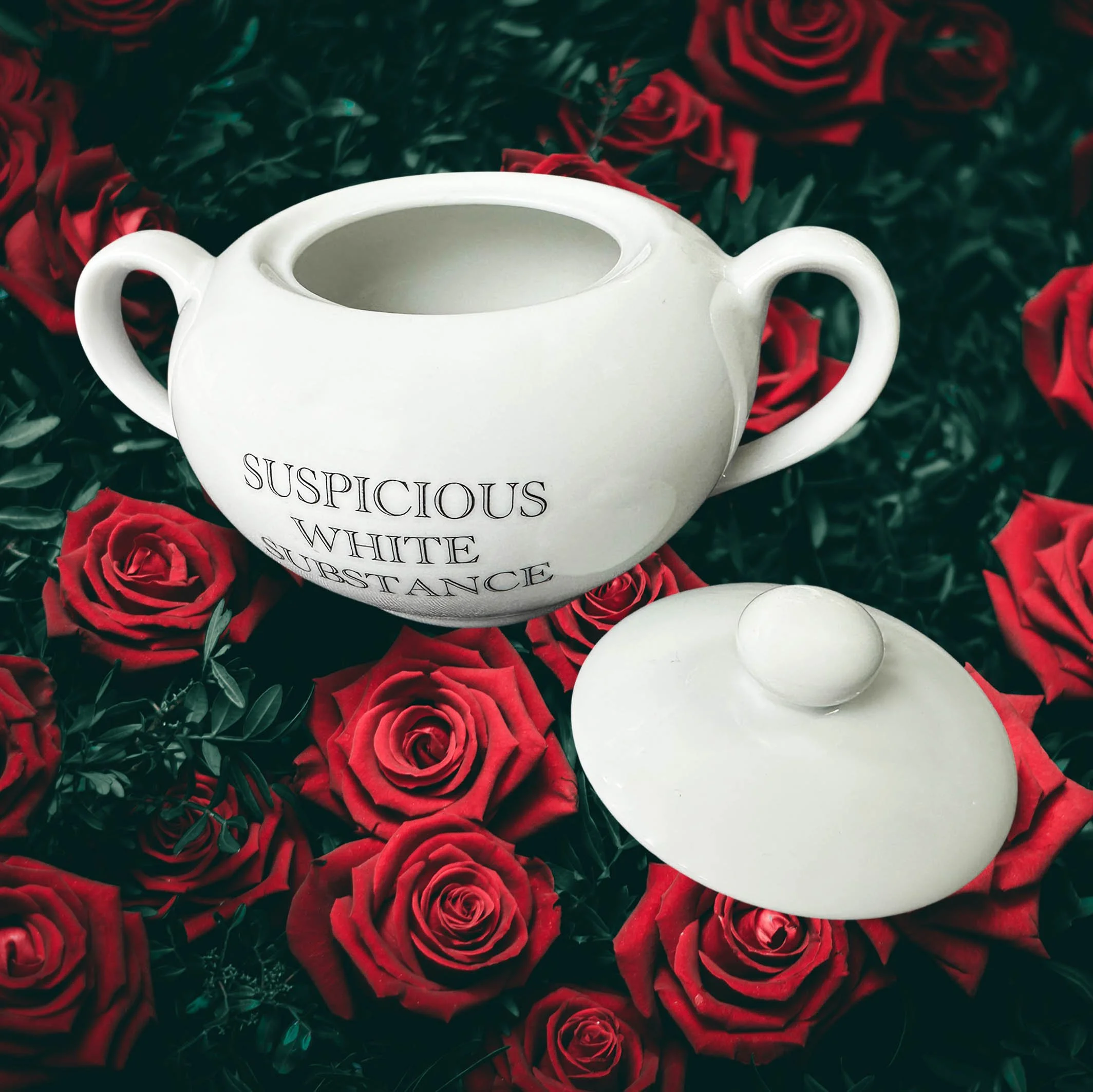 A white sugar bowl with handles and the words “suspicious white substance” in black lettering
