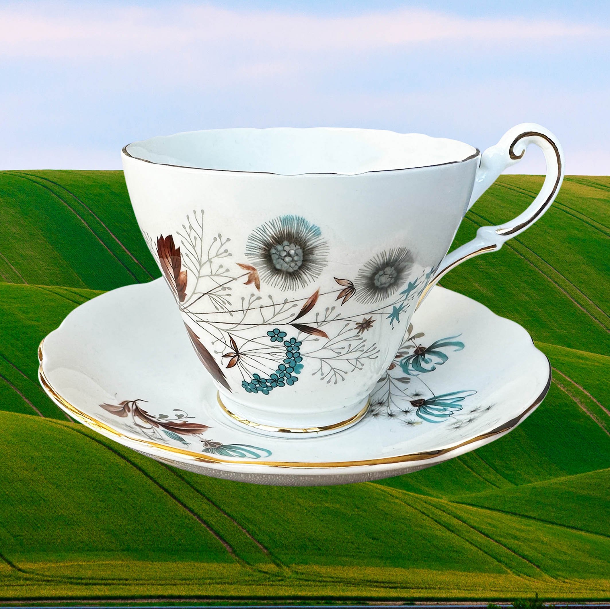 A vintage tea cup and saucer set with a blue and brown floral design, the words “woke up sexy as hell today” in black cursive writing