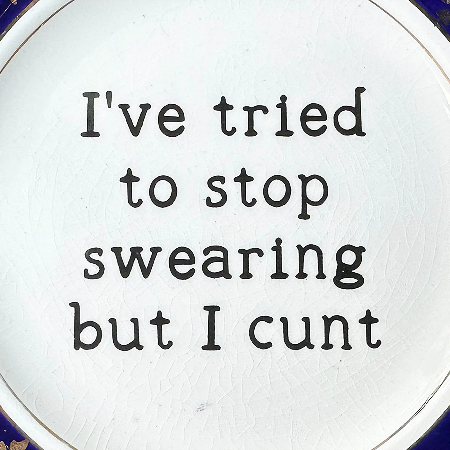 A vintage plate with a blue and gold border and a quote “I’ve tried to stop swearing but I cunt”