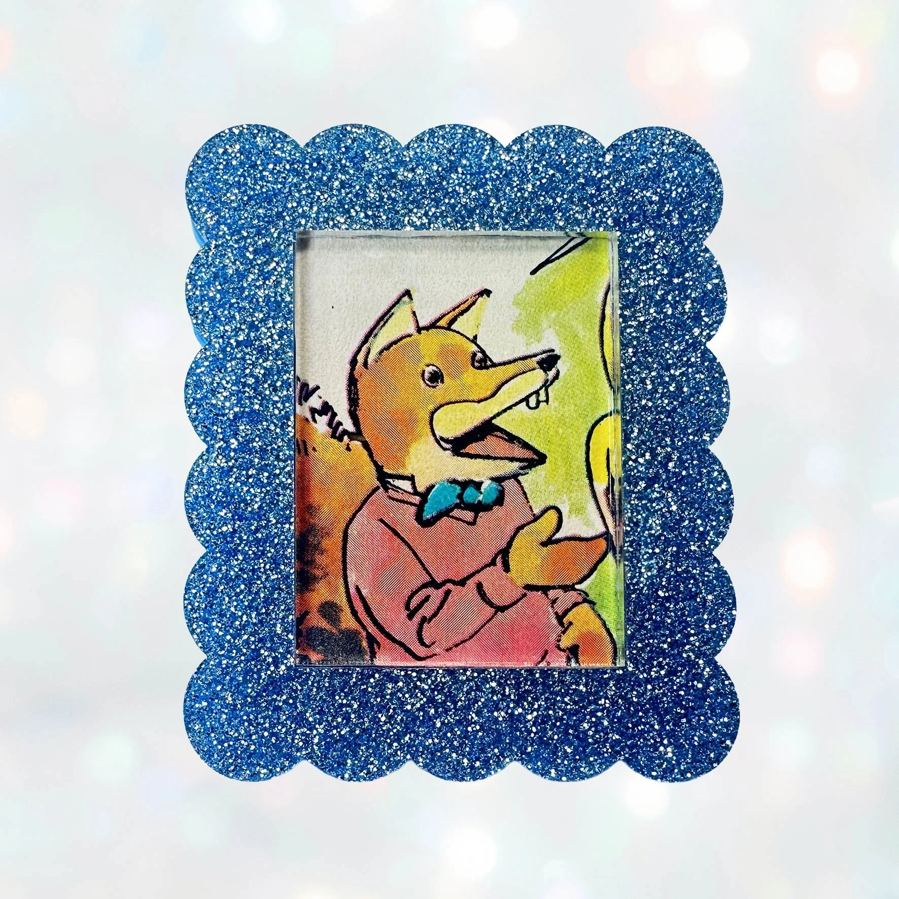 A light blue glitter acrylic brooch featuring a picture of Basil Brush