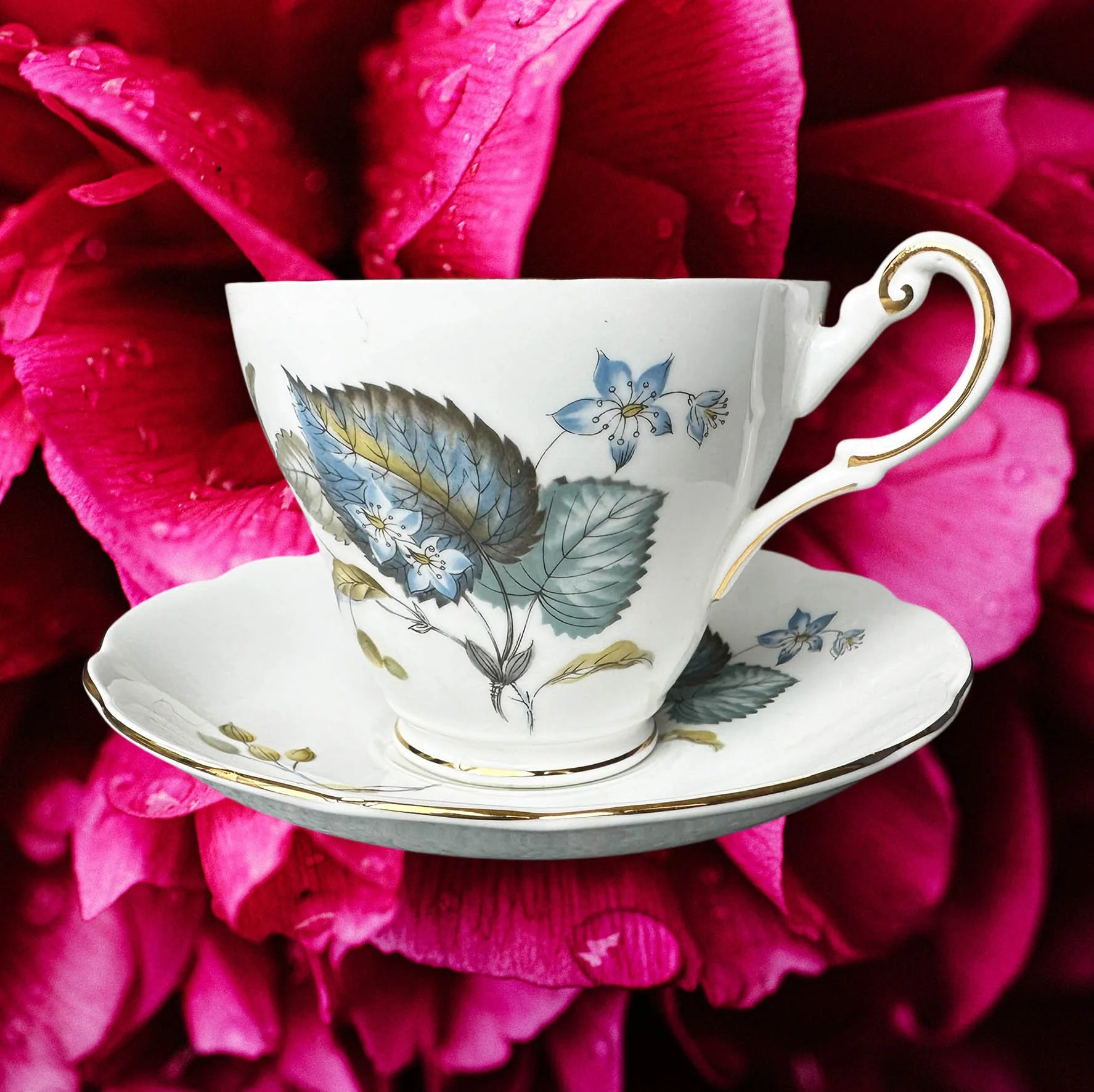 A vintage tea cup with a blue floral design and the words "maybe swearing will help" in black writing