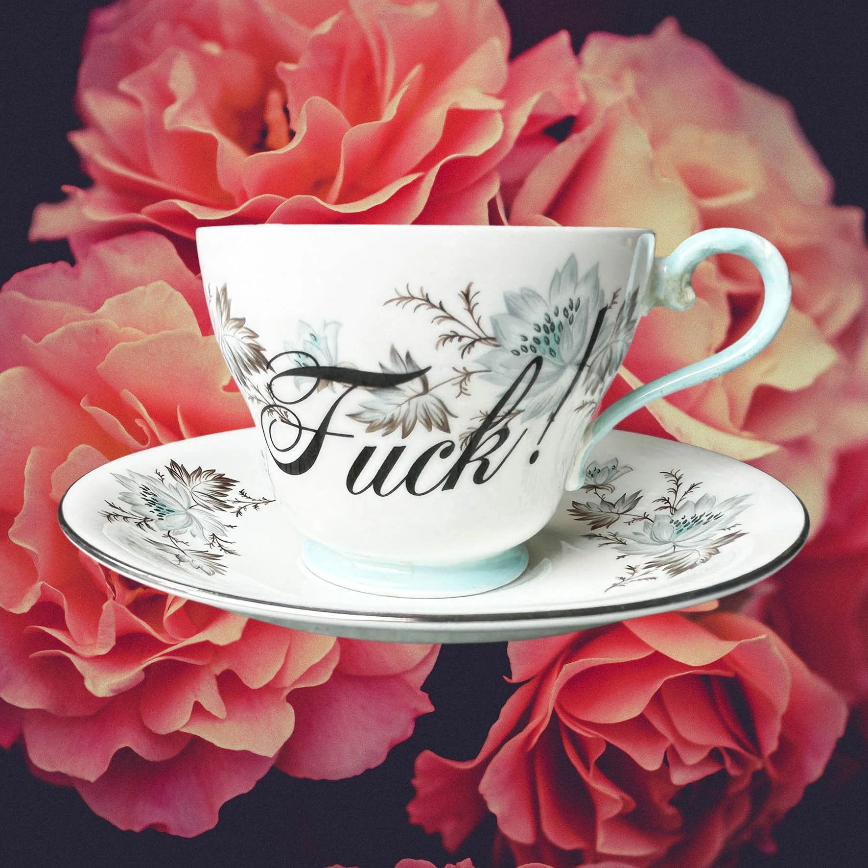 a vintage tea cup and saucer with a blue floral design and the word "fuck!" in black writing