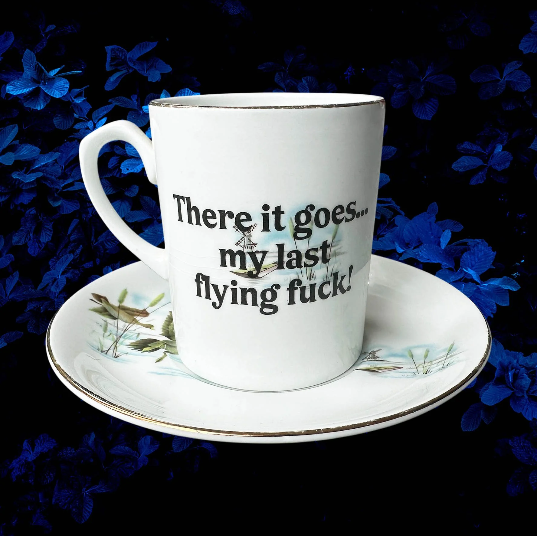 A vintage cup and saucer with a picture of ducks and the words "there it goes...my last flying fuck" in black lettering