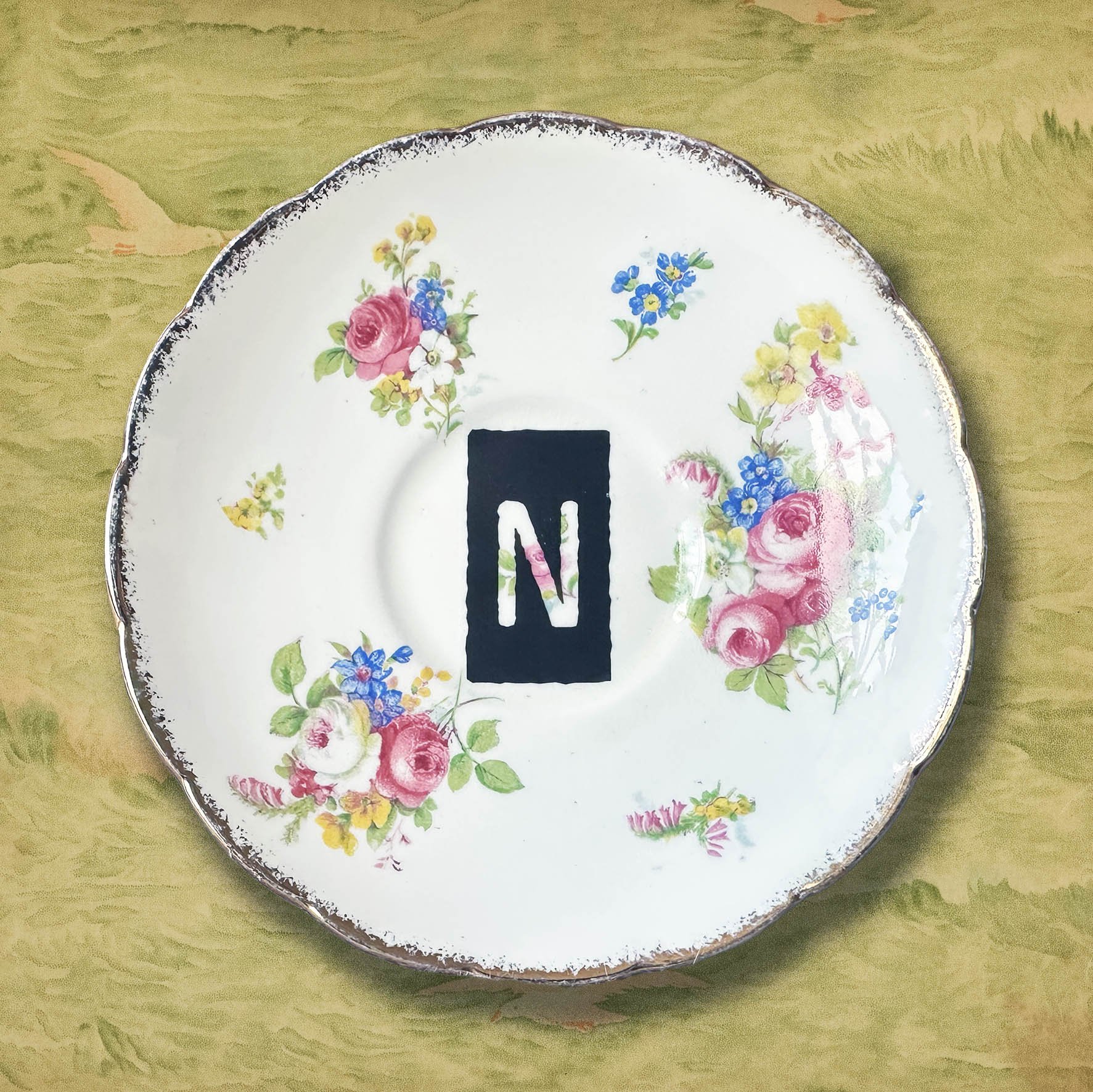 A vintage saucer with an orange black letter N