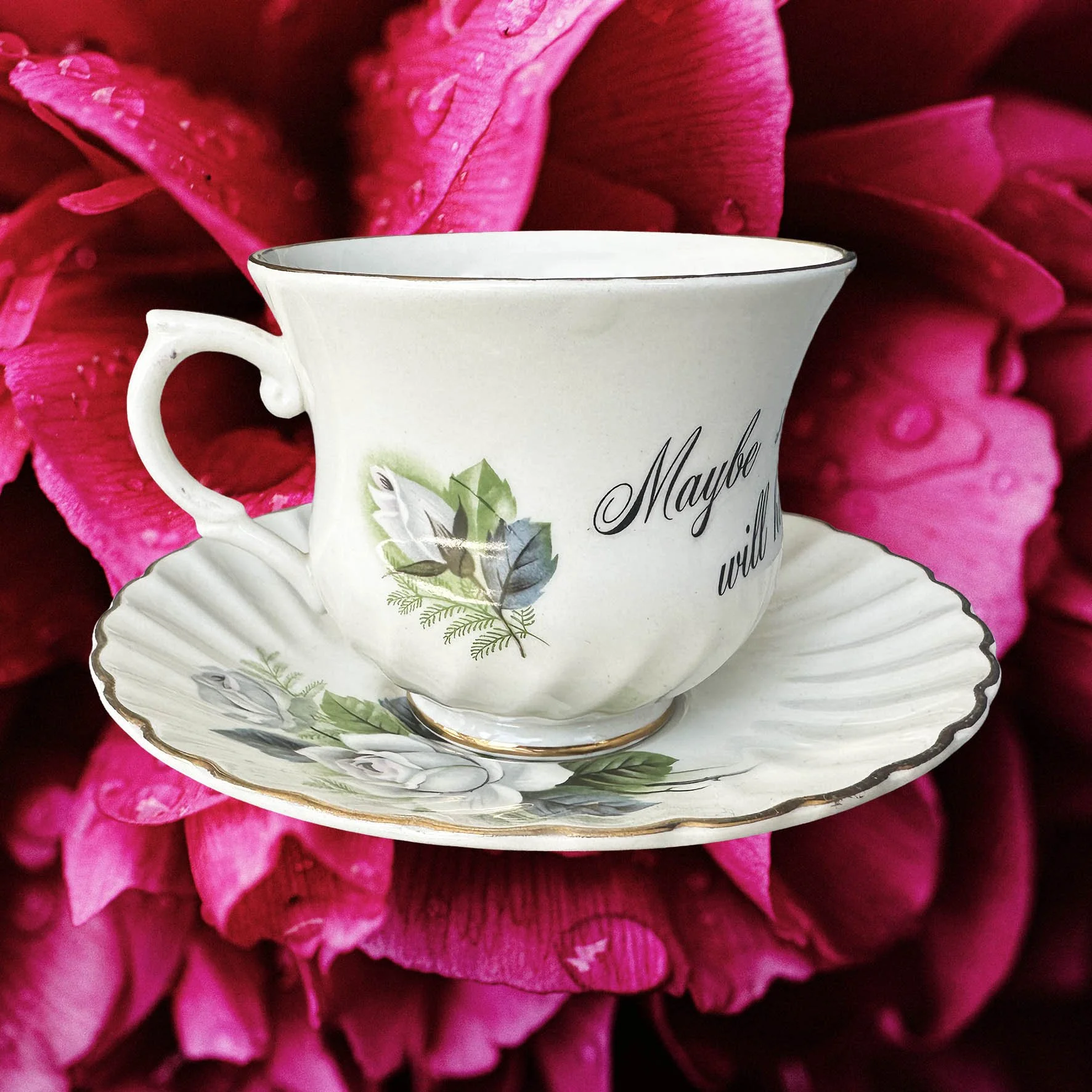 A vintage tea cup with a blue floral design and the words "maybe swearing will help" in black writing