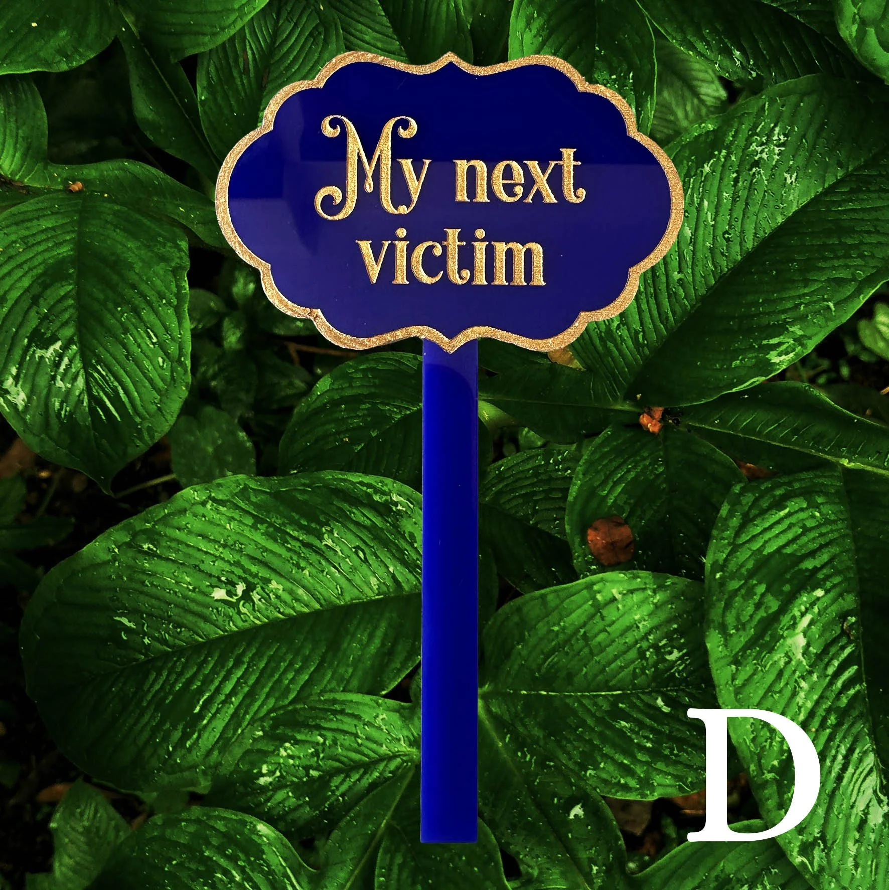 D, blue acrylic planter stick label with the words "my next victim" in gold writing