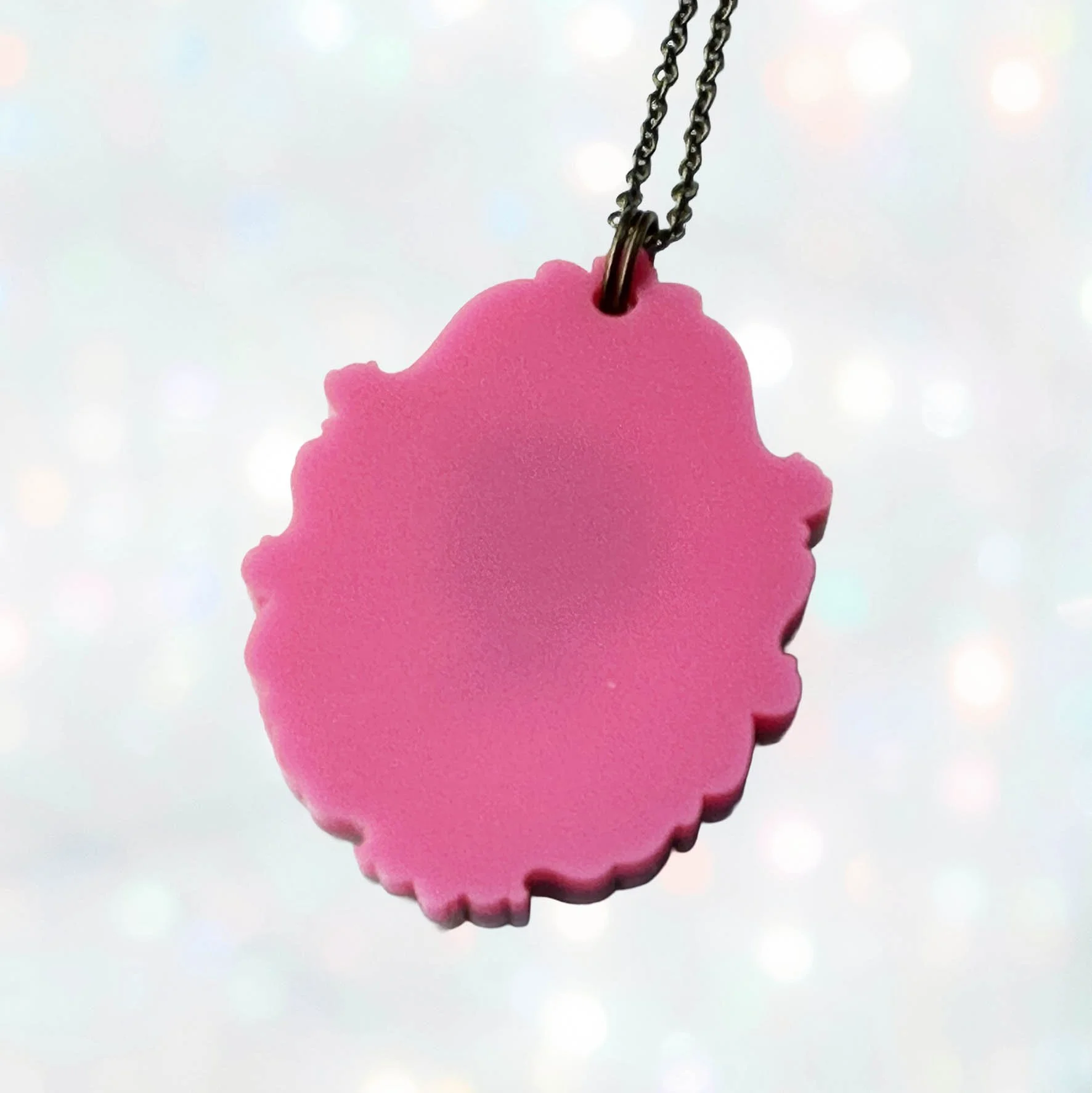 A laser cut pink and gold acrylic cameo style necklace featuring a silhouette