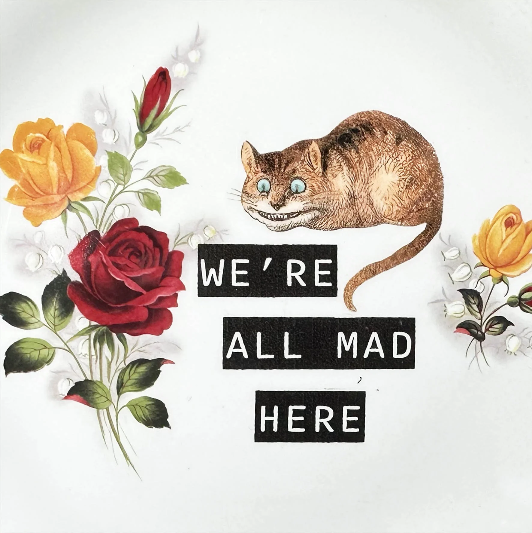 A vintage plate with a picture of the Cheshire Cat and the quote “we’re all made here”