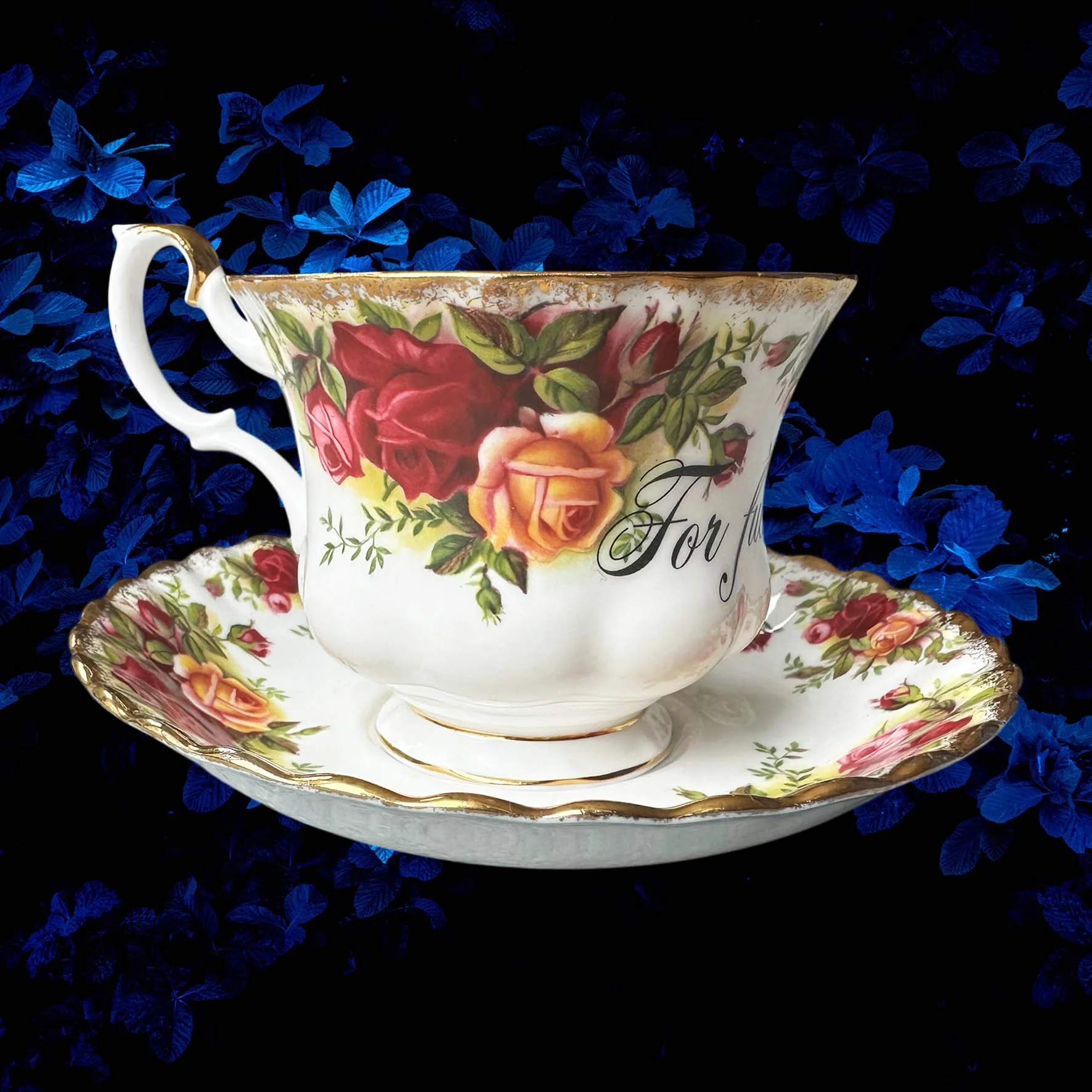 a vintage tea cup with a red rose design and the words "for fuck's sake" in black writing