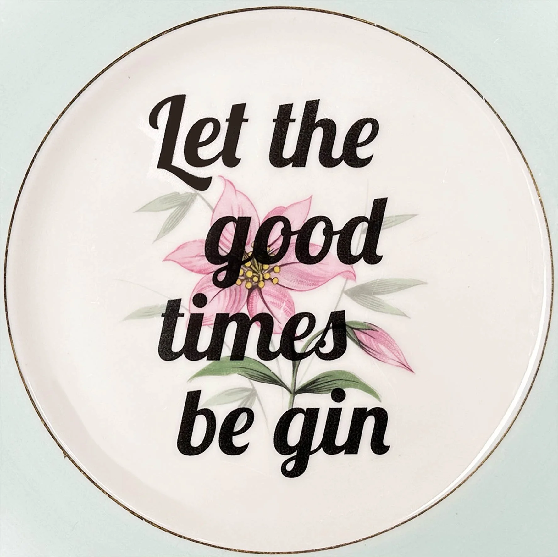A vintage plate with a pink floral design and the quote “let the good times be gin”