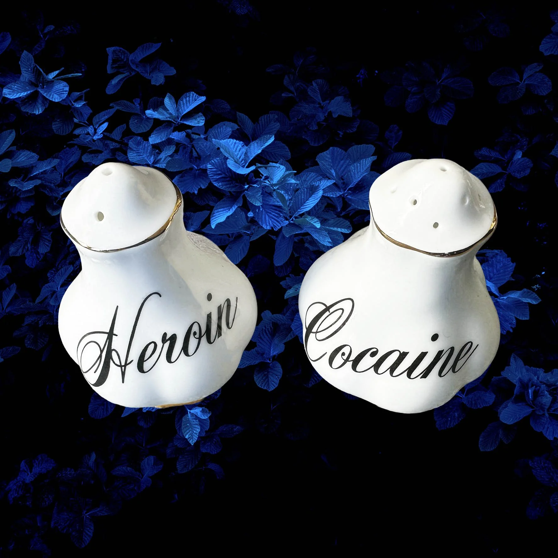 White salt and pepper shakers with the words “heroin” and “cocaine” in black cursive writing