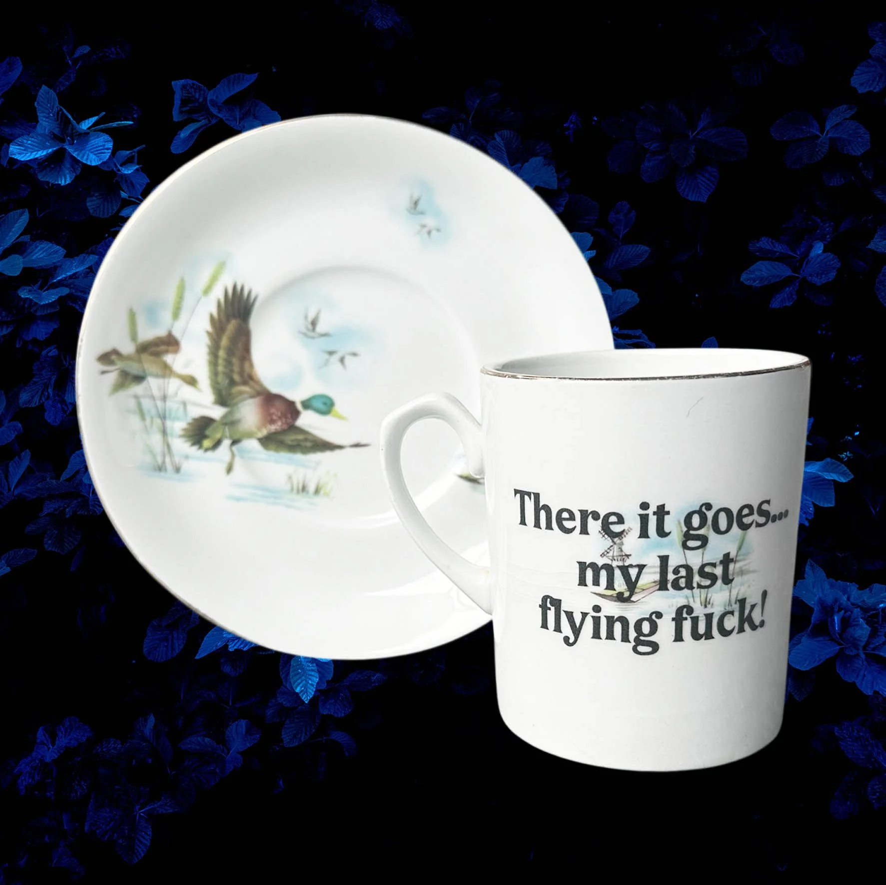 A vintage cup and saucer with a picture of ducks and the words "there it goes...my last flying fuck" in black lettering