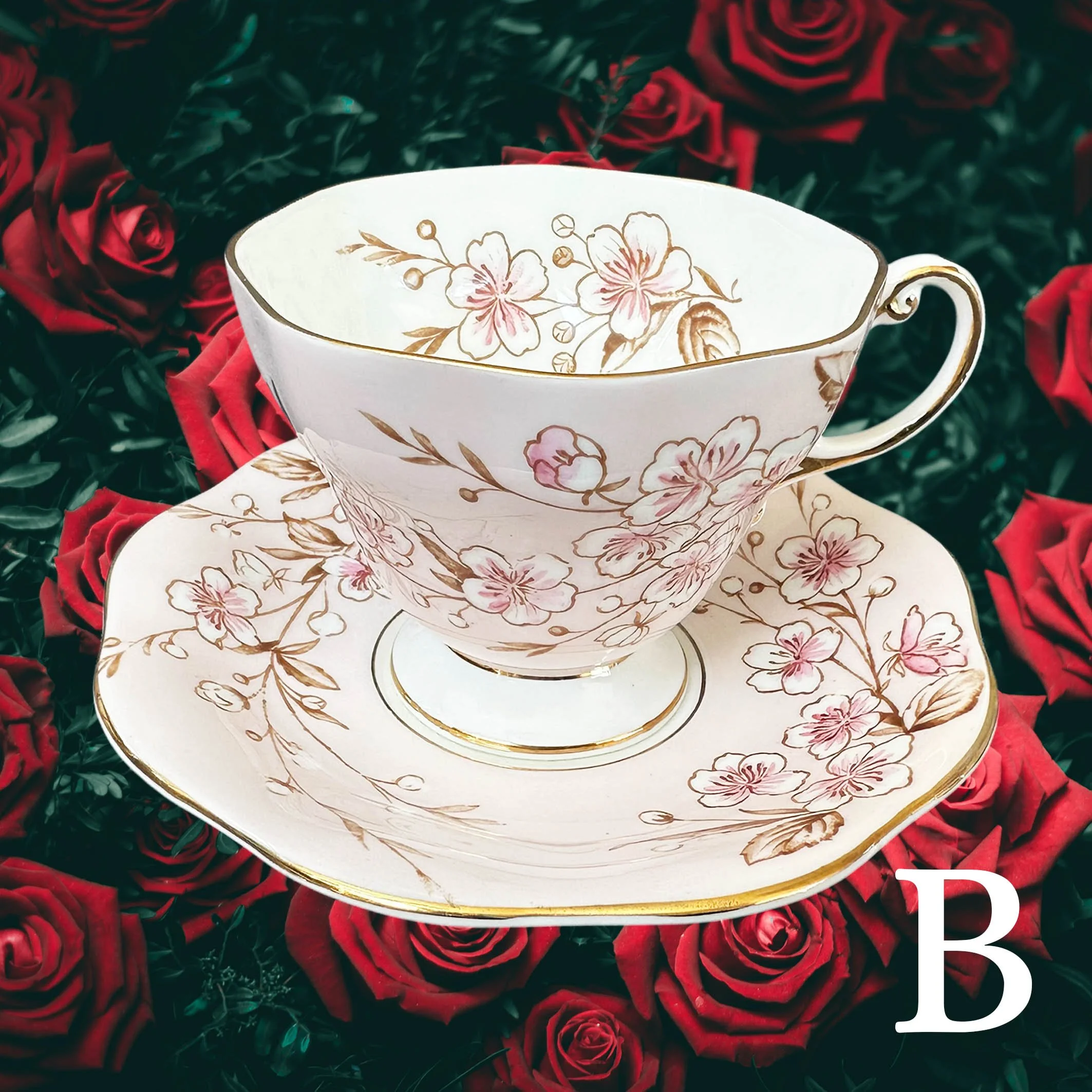 A soft pink vintage tea cup and saucer set with a pink floral design, with the words "badass bitch" in black cursive writing