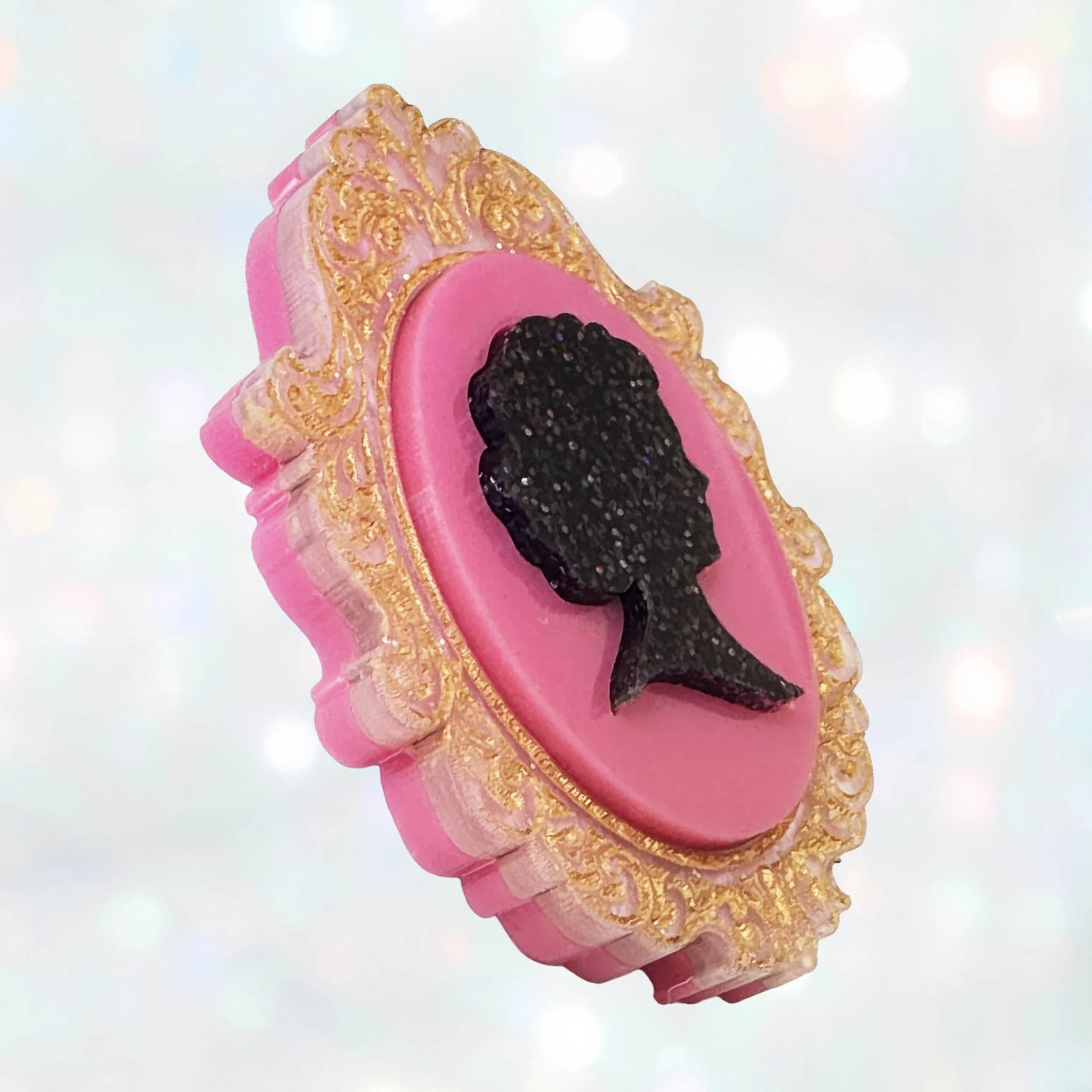 A pink, black and gold glitter laser cut acrylic cameo style brooch featuring a silhouette