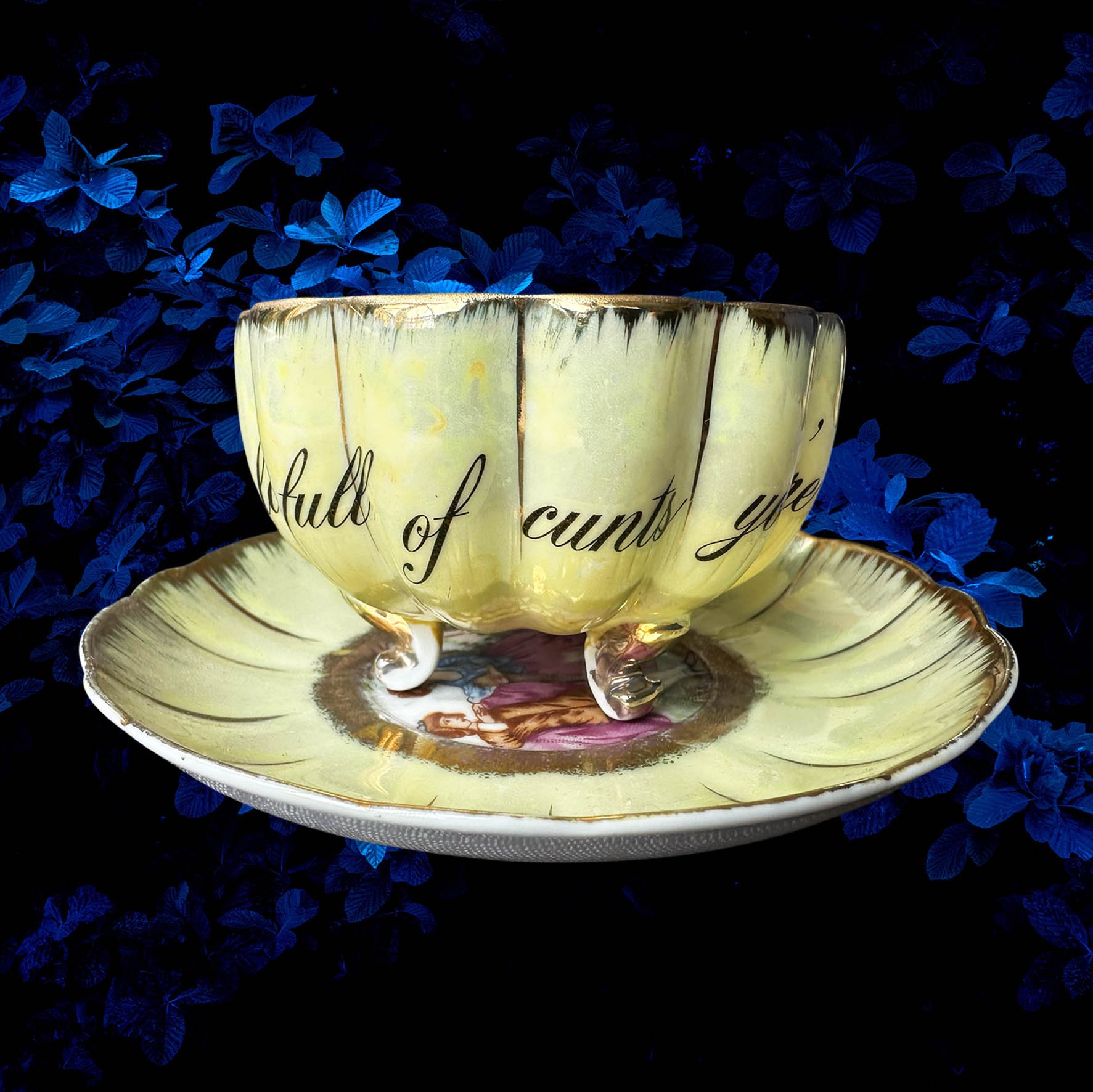 A yellow scalloped shaped tea cup with a picture of a couple and the words "In a world full of cunts you're my favourite"