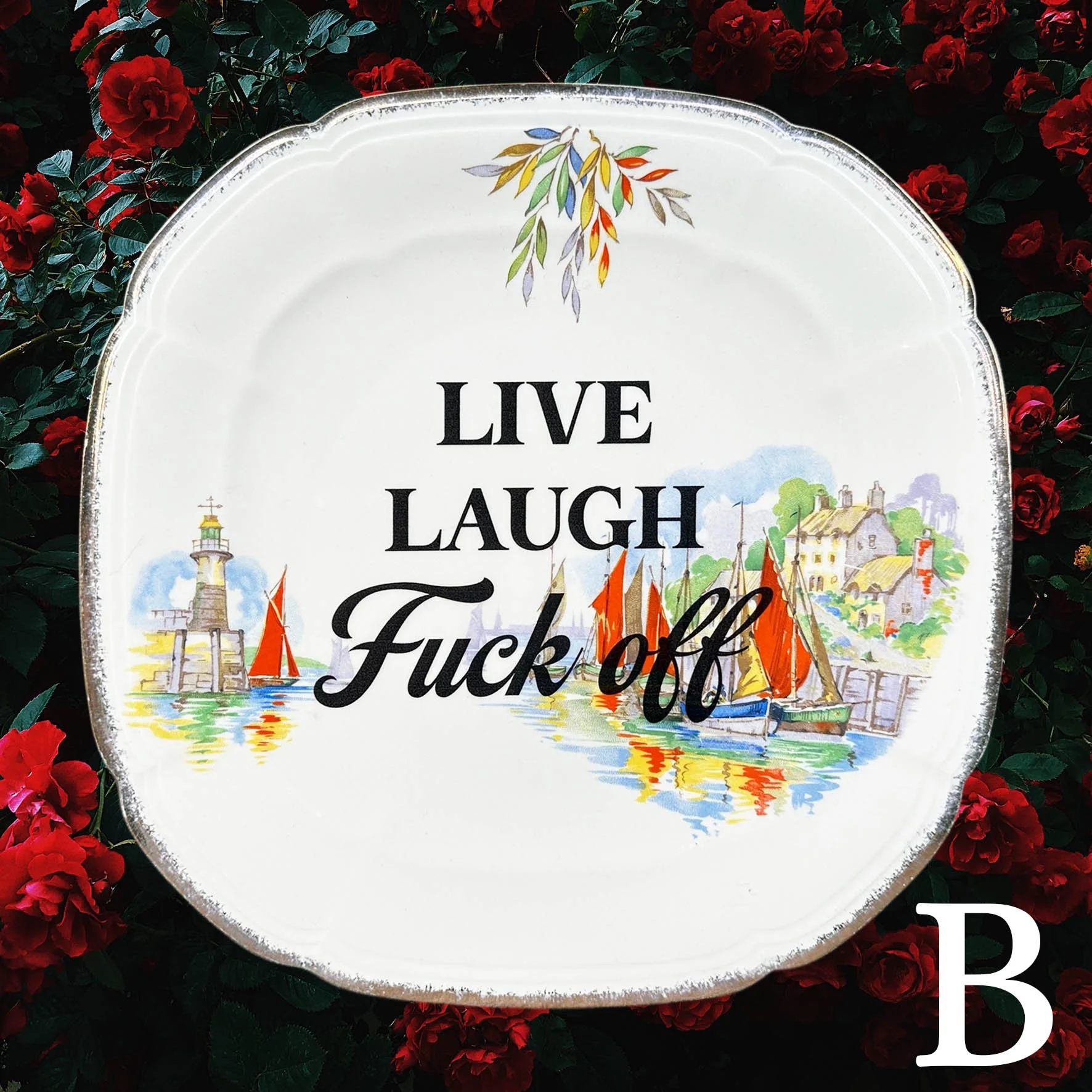 A vintage plate with the quote “live laugh fuck off” in black writing